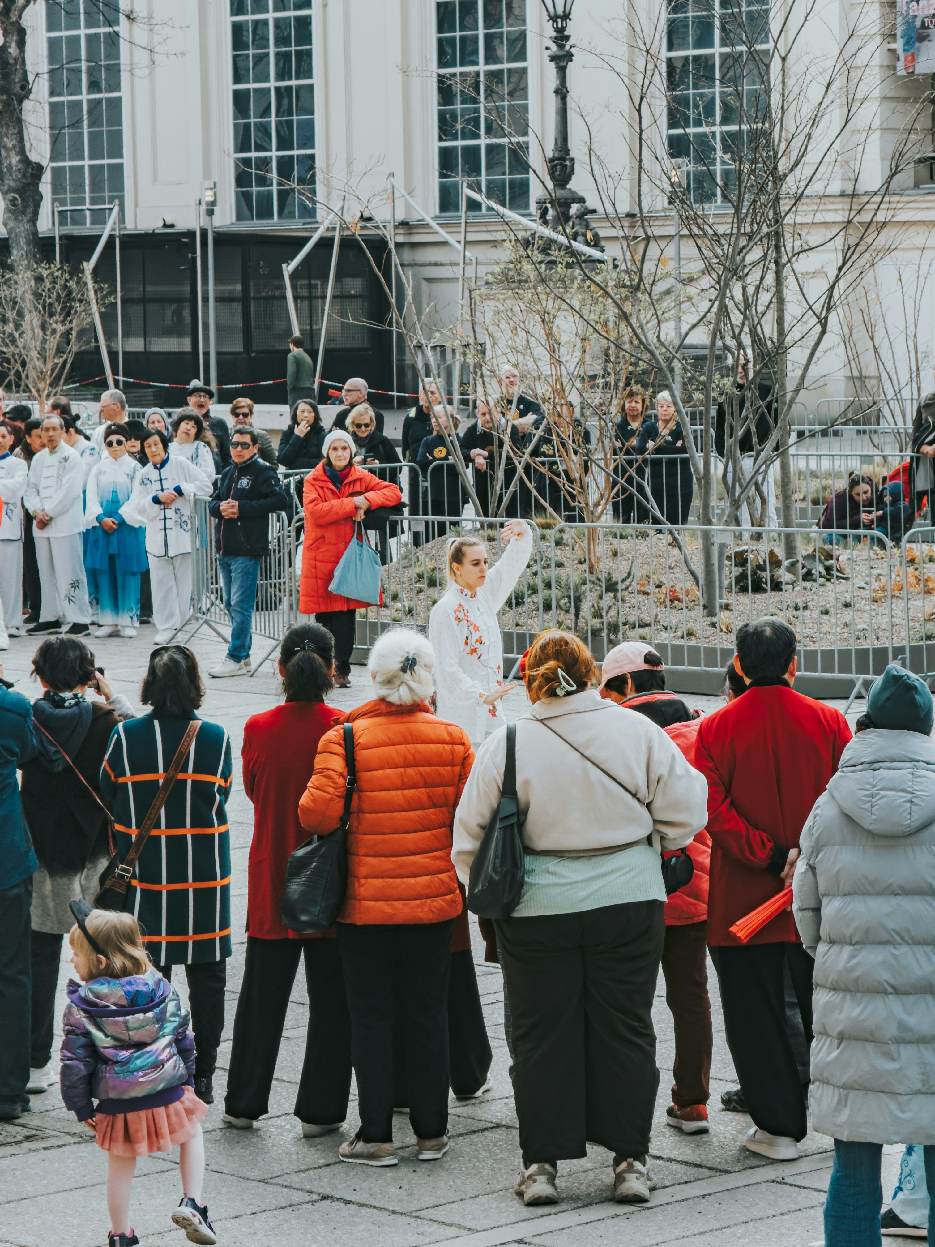People practice tai chi in an outdoor plaza.