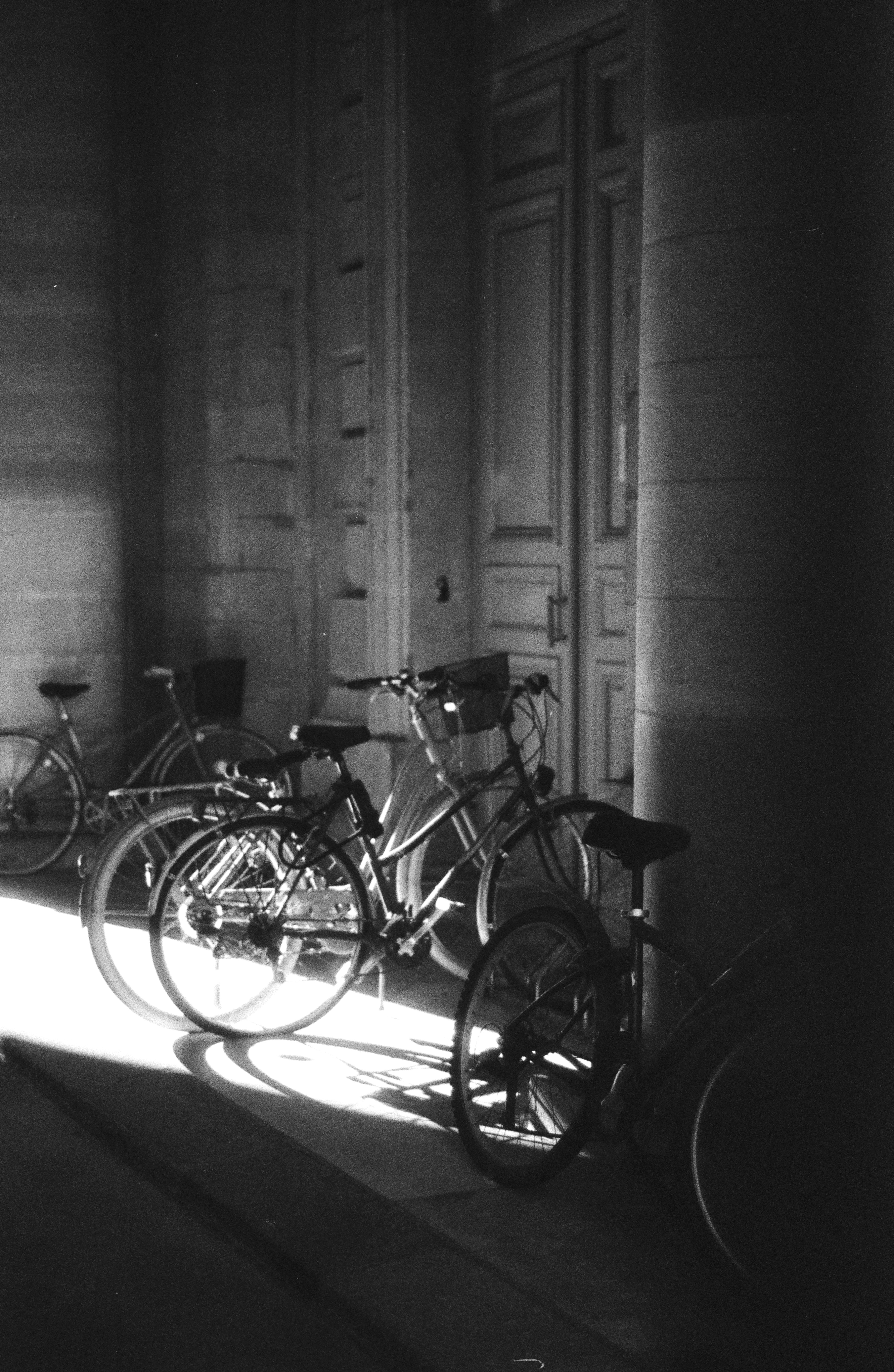 Diverse biciclette parcheggiate in un corridoio illuminato dal sole.