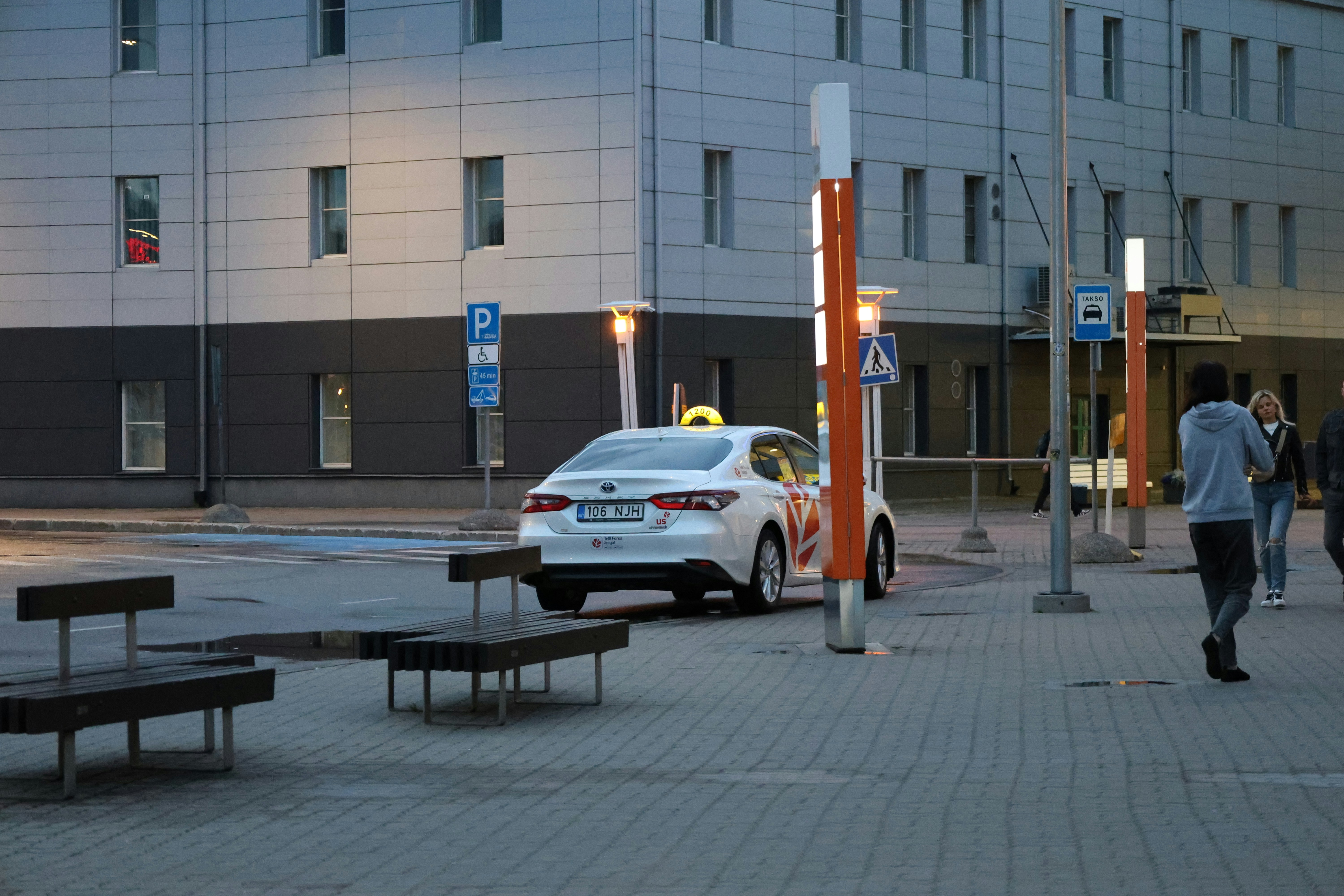 White taxi parked on a city street at dusk.