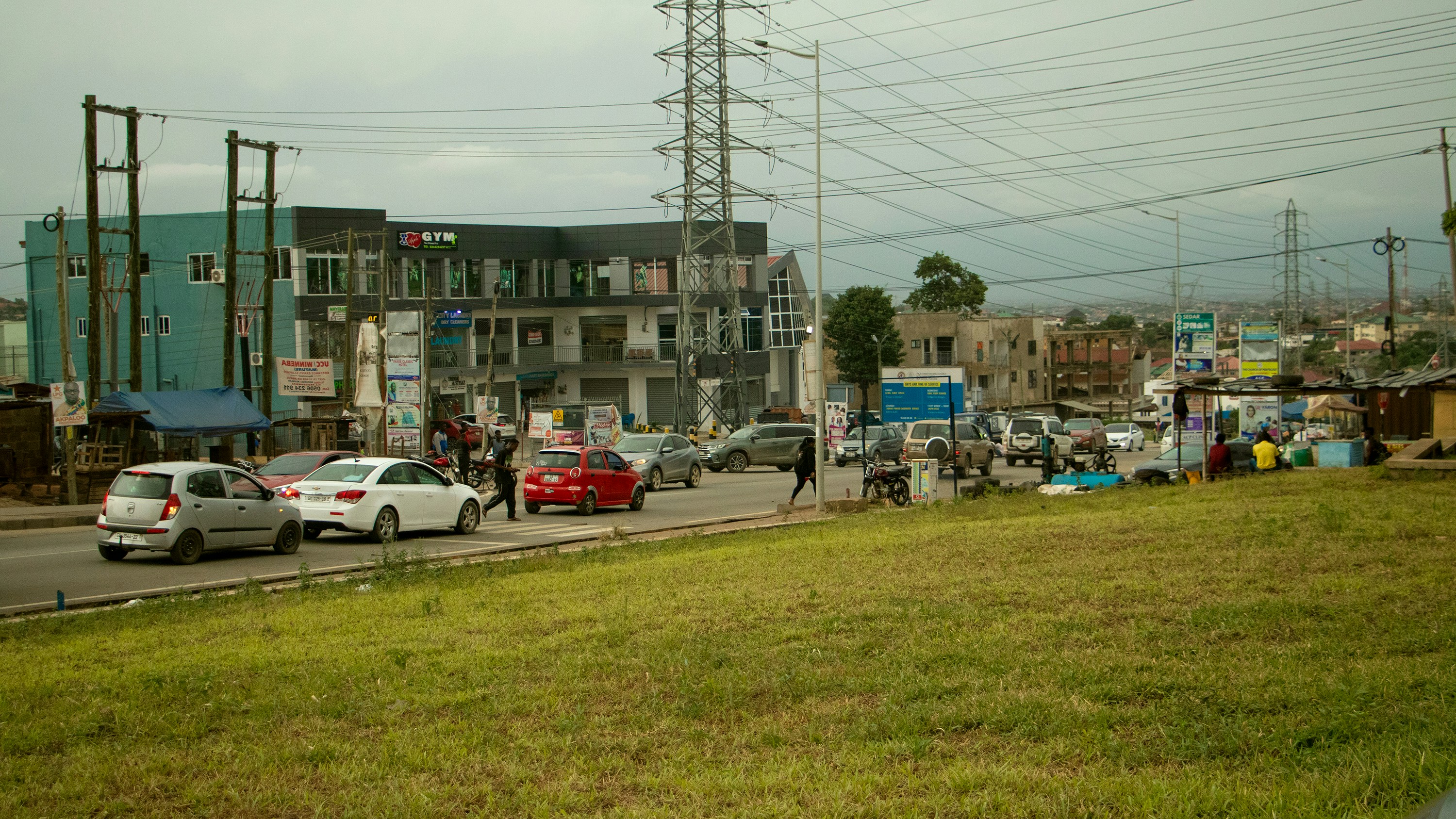 Cars on a busy road with buildings and power lines.