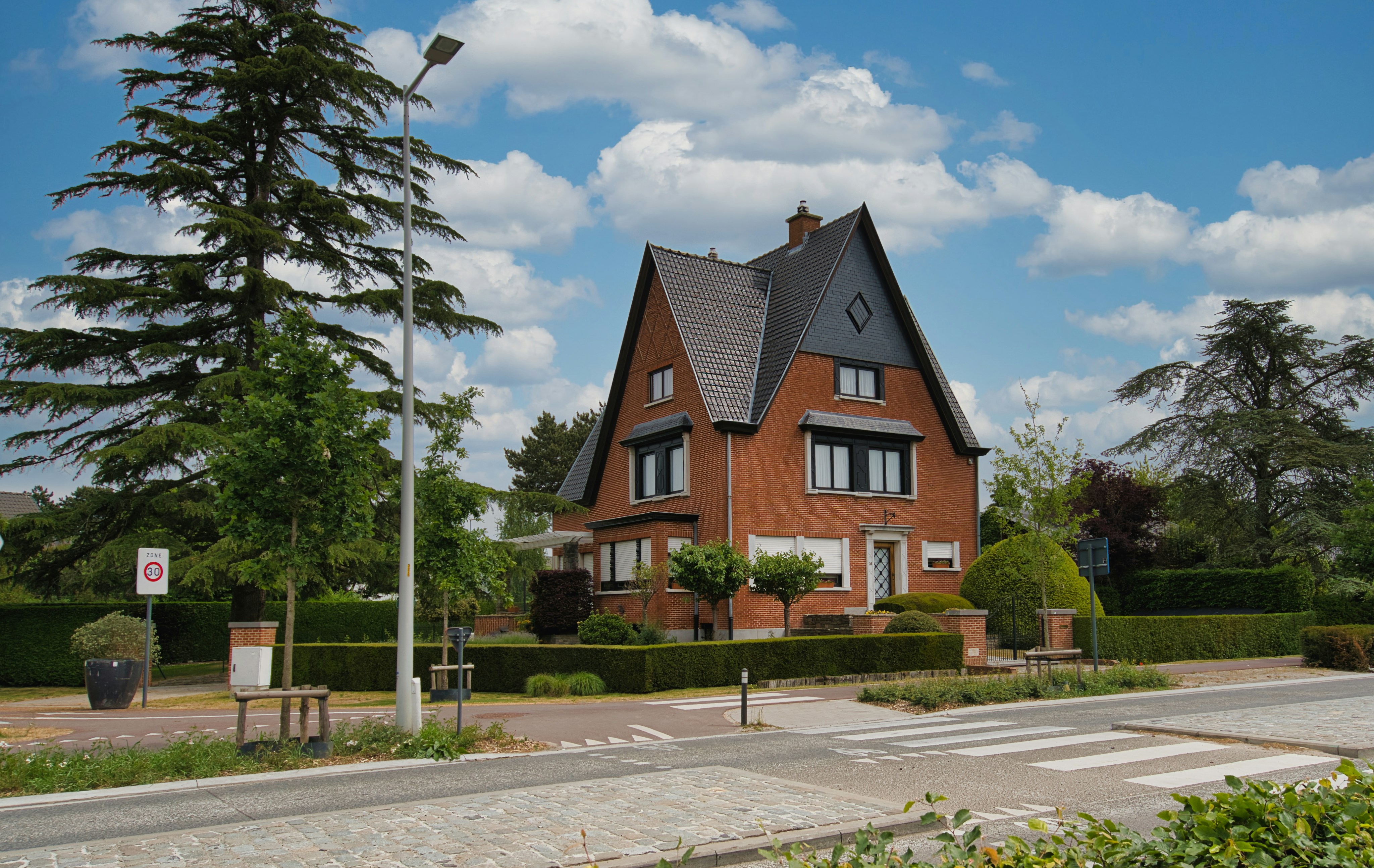 A brick house with a steep roof and garden.