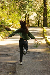 A woman runs down a wooded path
