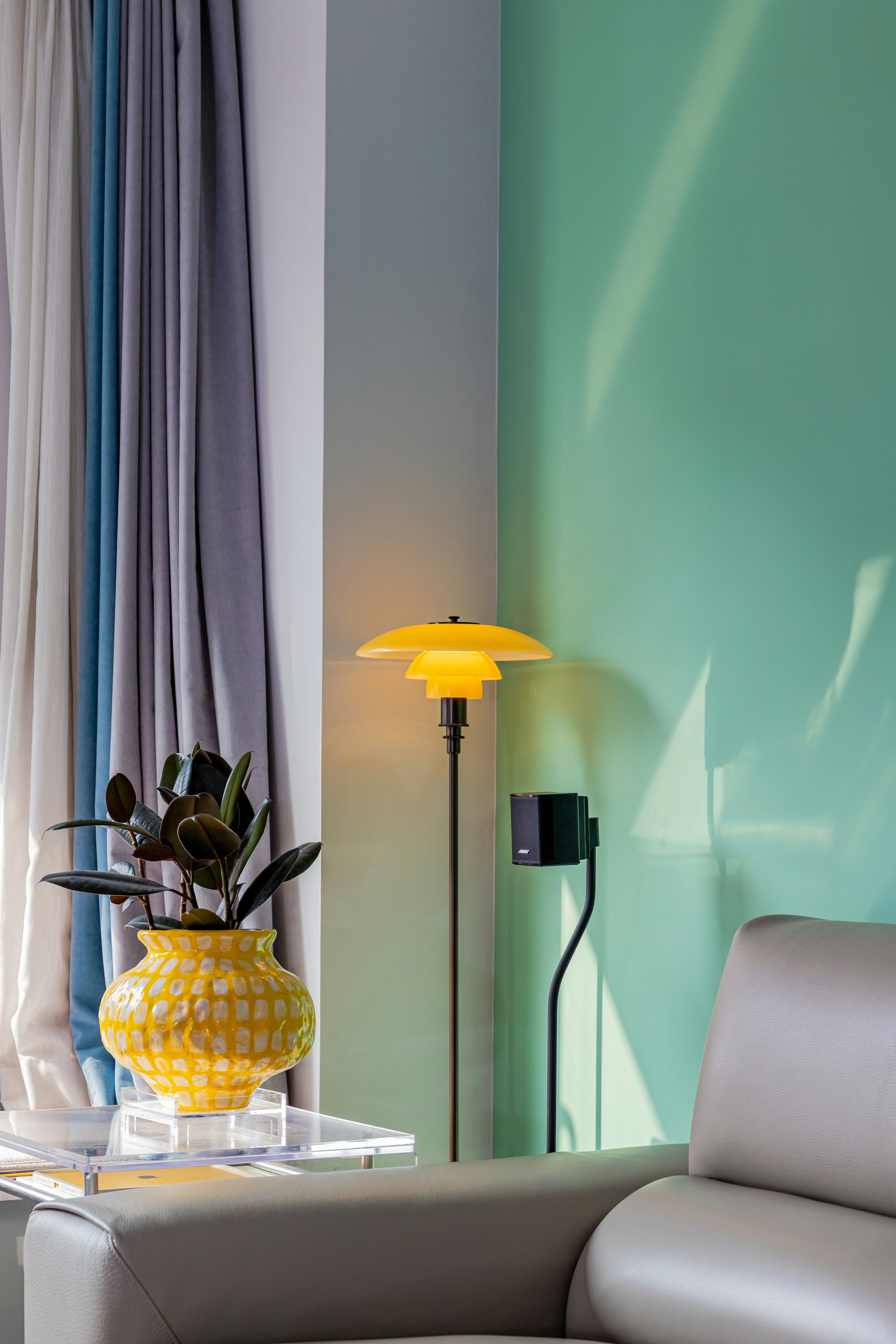 Yellow lamp and plant next to a sofa.