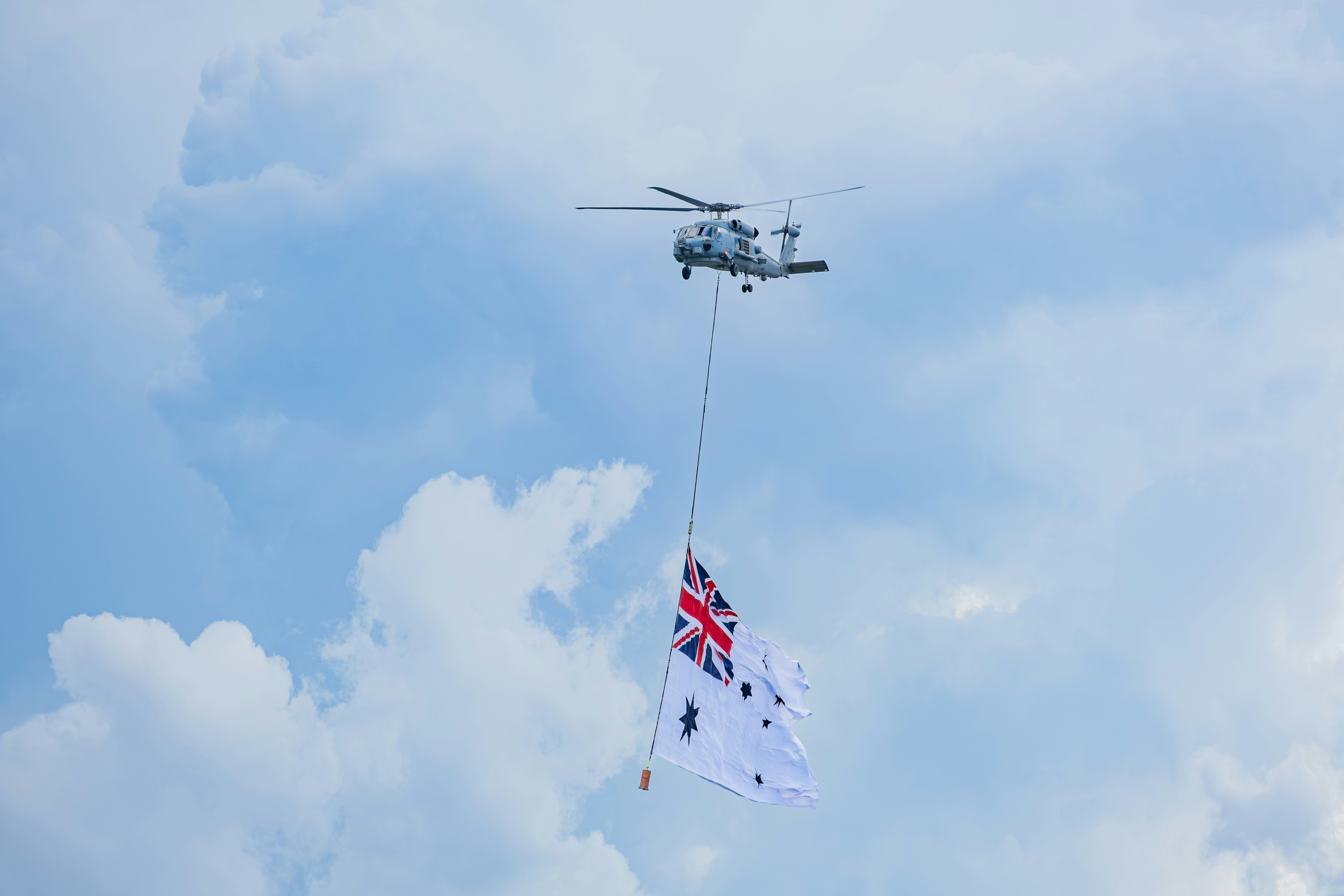 Helicopter flies with a flag against a cloudy sky