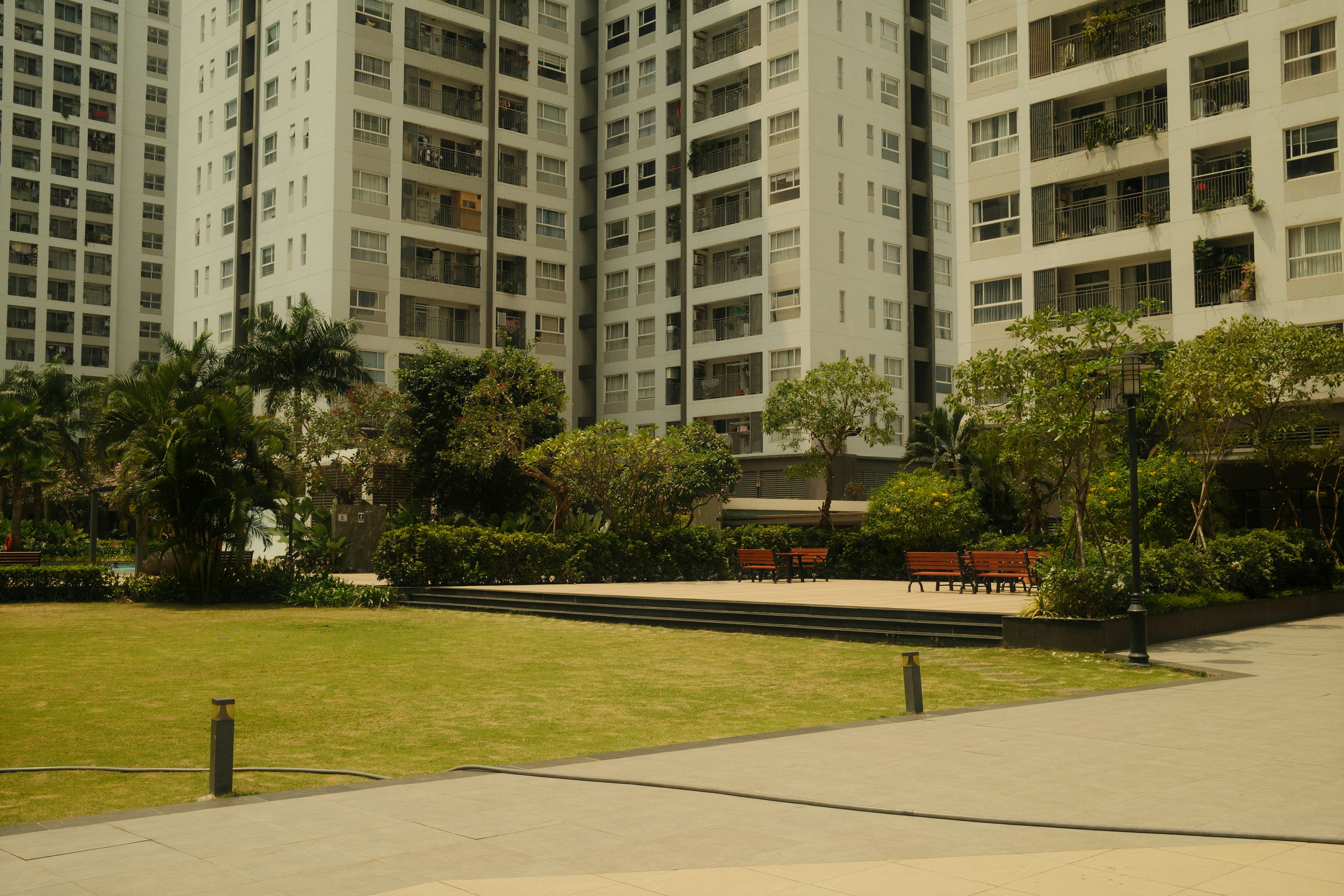 Apartment buildings overlook a grassy courtyard with benches.