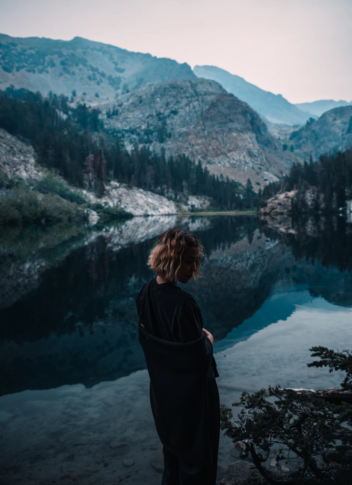 Person an einem ruhigen Bergsee als Symbol für Abstand und bewusste Pause