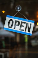 An open sign hanging on a glass door