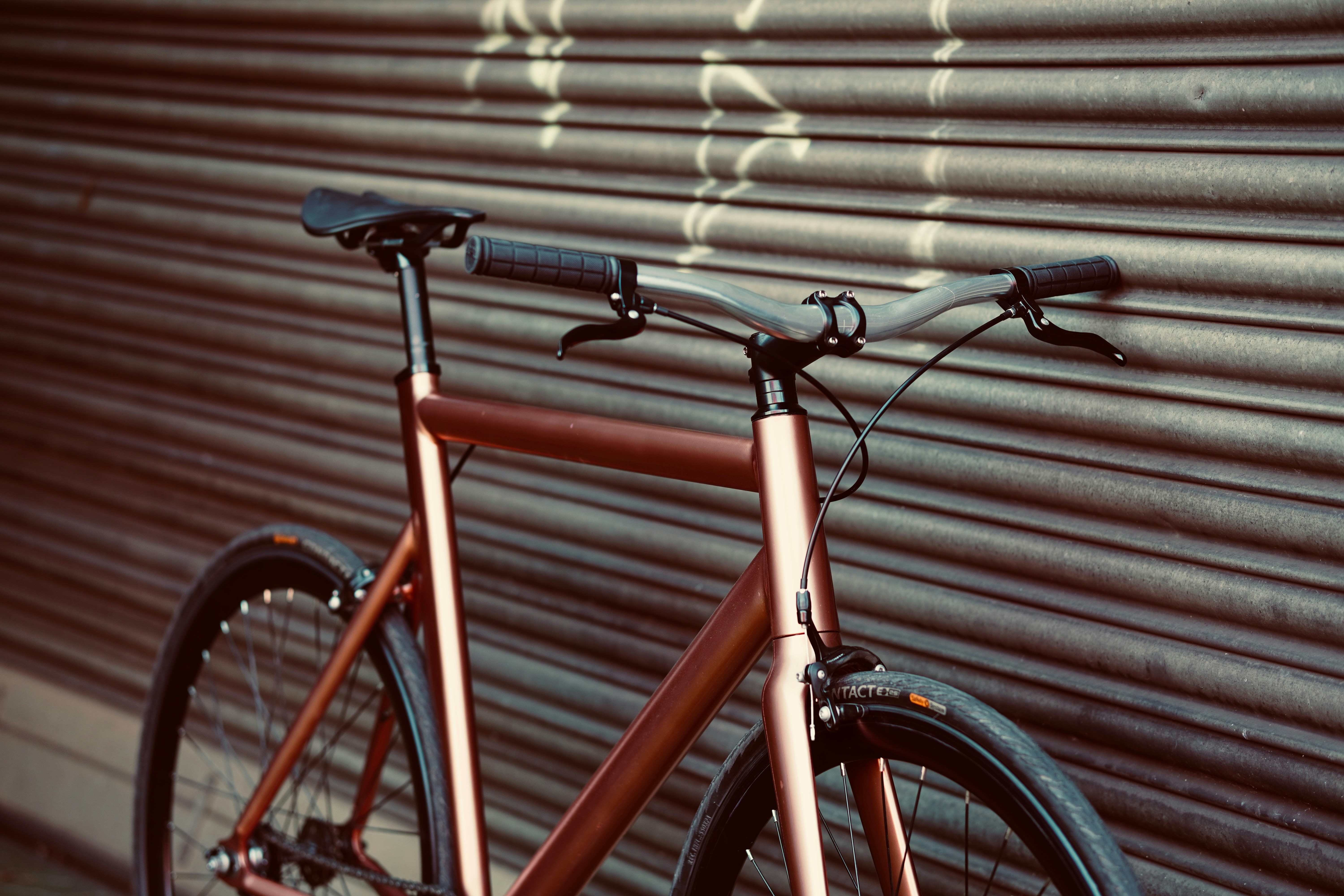 A close-up of a copper bicycle leaning against a wall.
