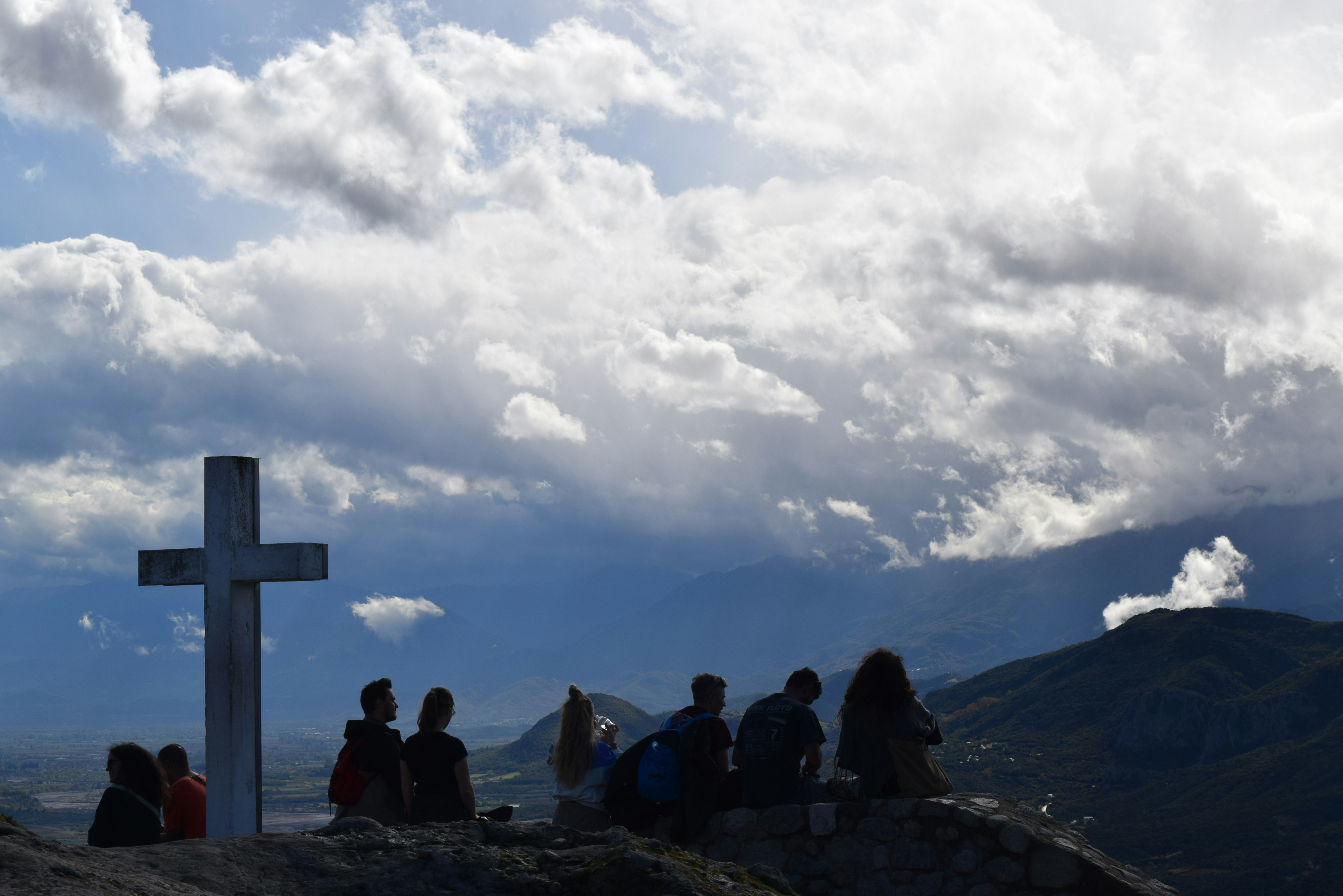 People gather on a hilltop near a cross