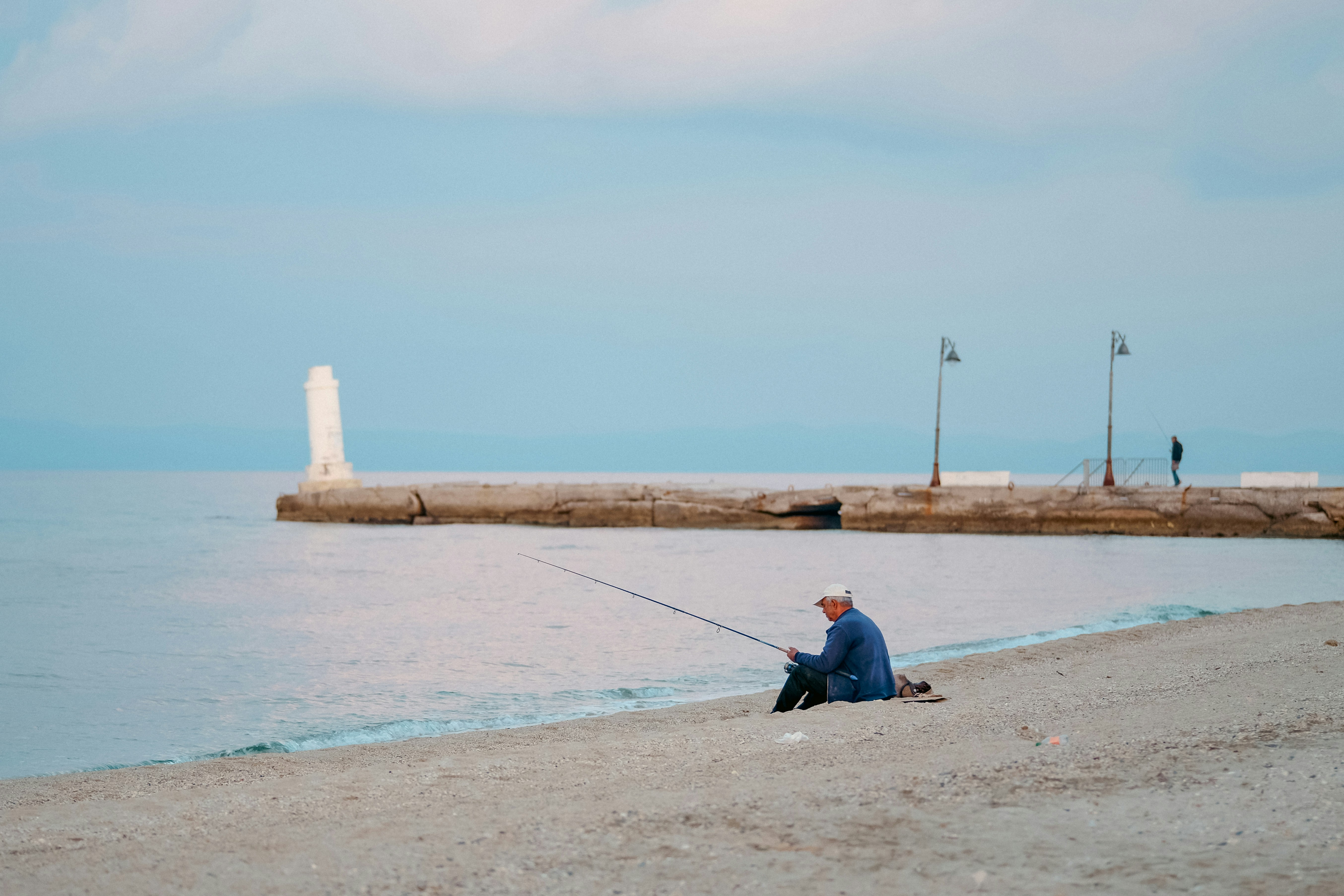 Un homme pêcheant au bord de la mer près d’un quai.