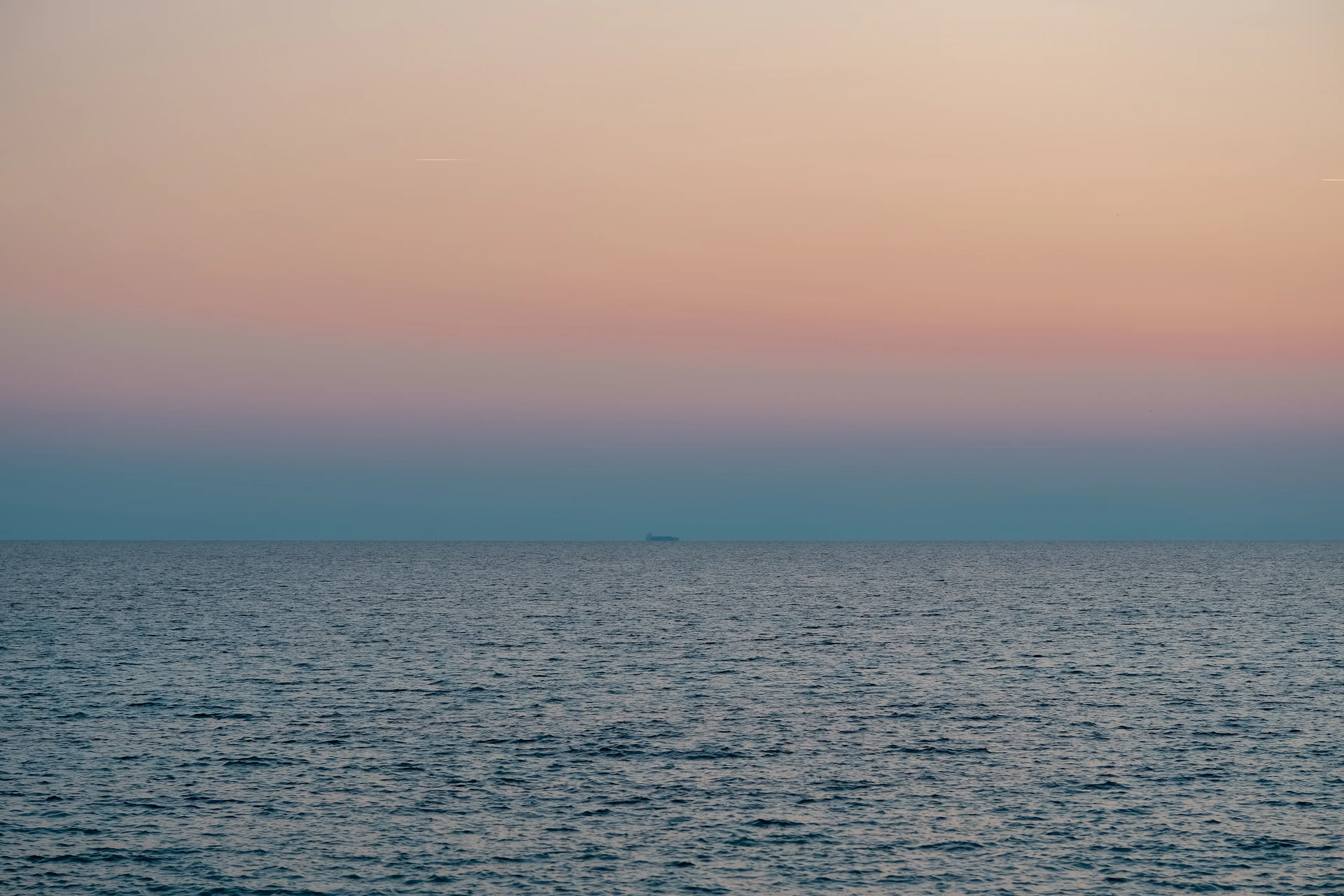 Calm ocean under a pastel sunset sky.
