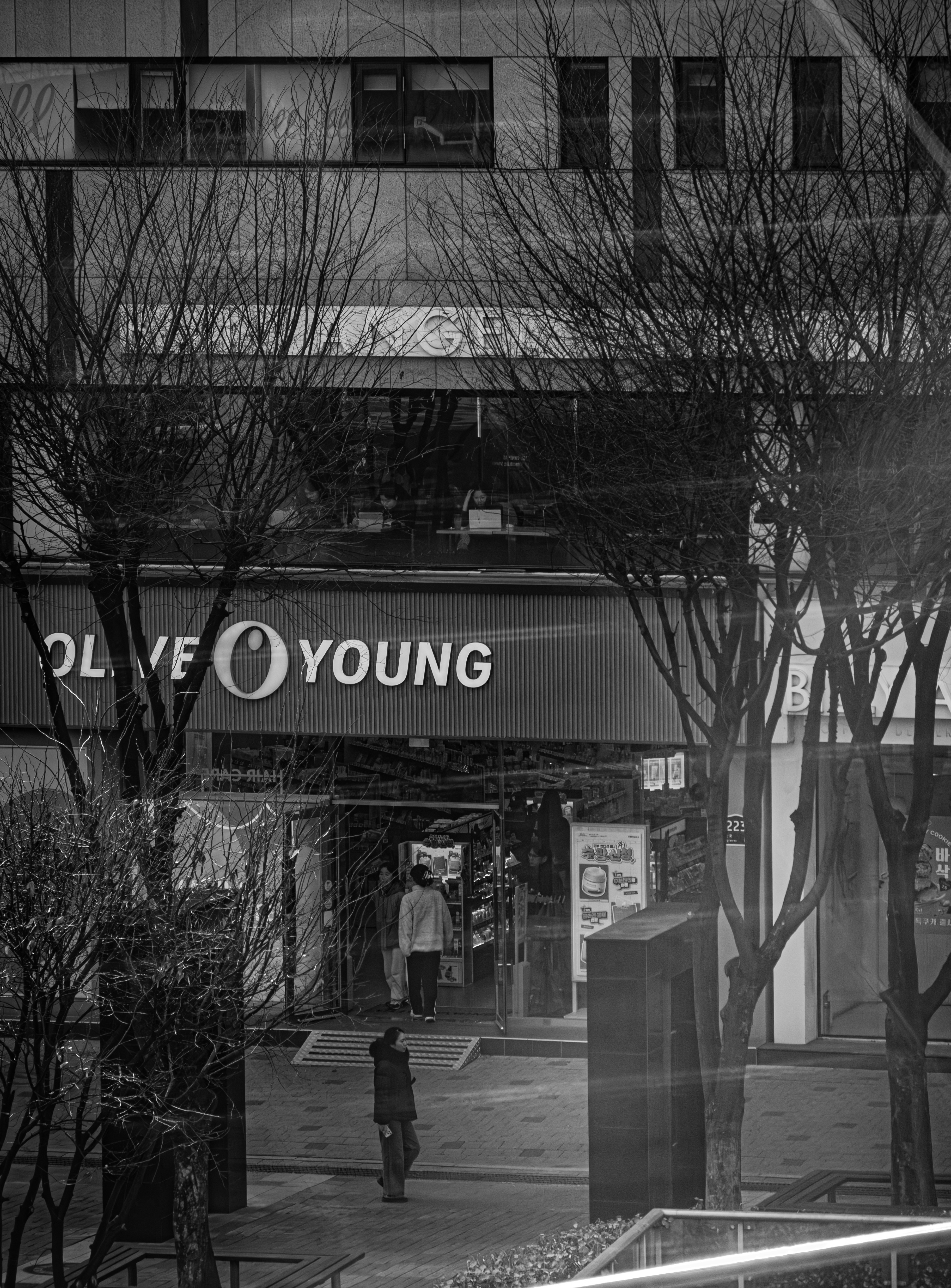 Black and white of a street with olive young store.