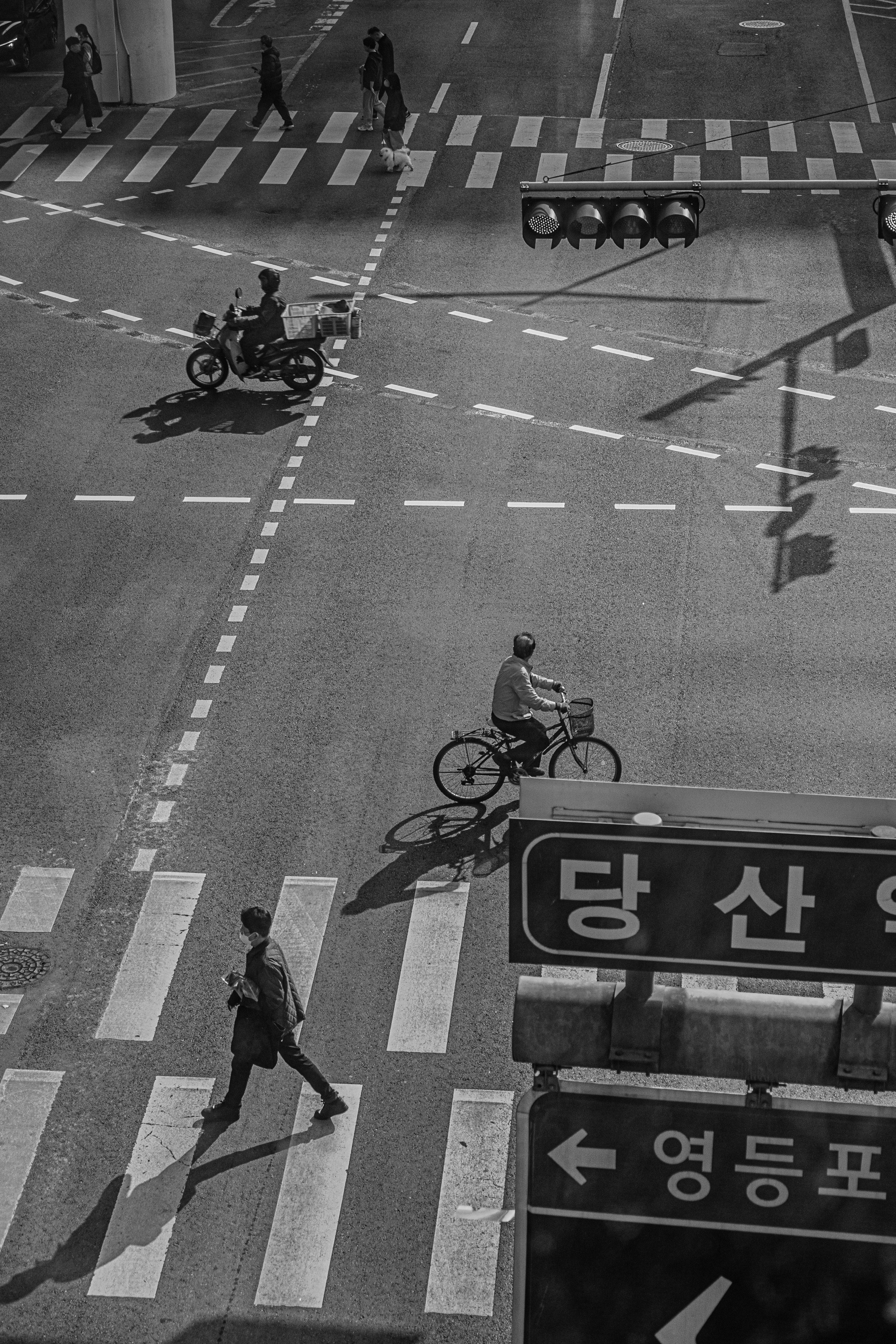 People and vehicles cross a busy street intersection.
