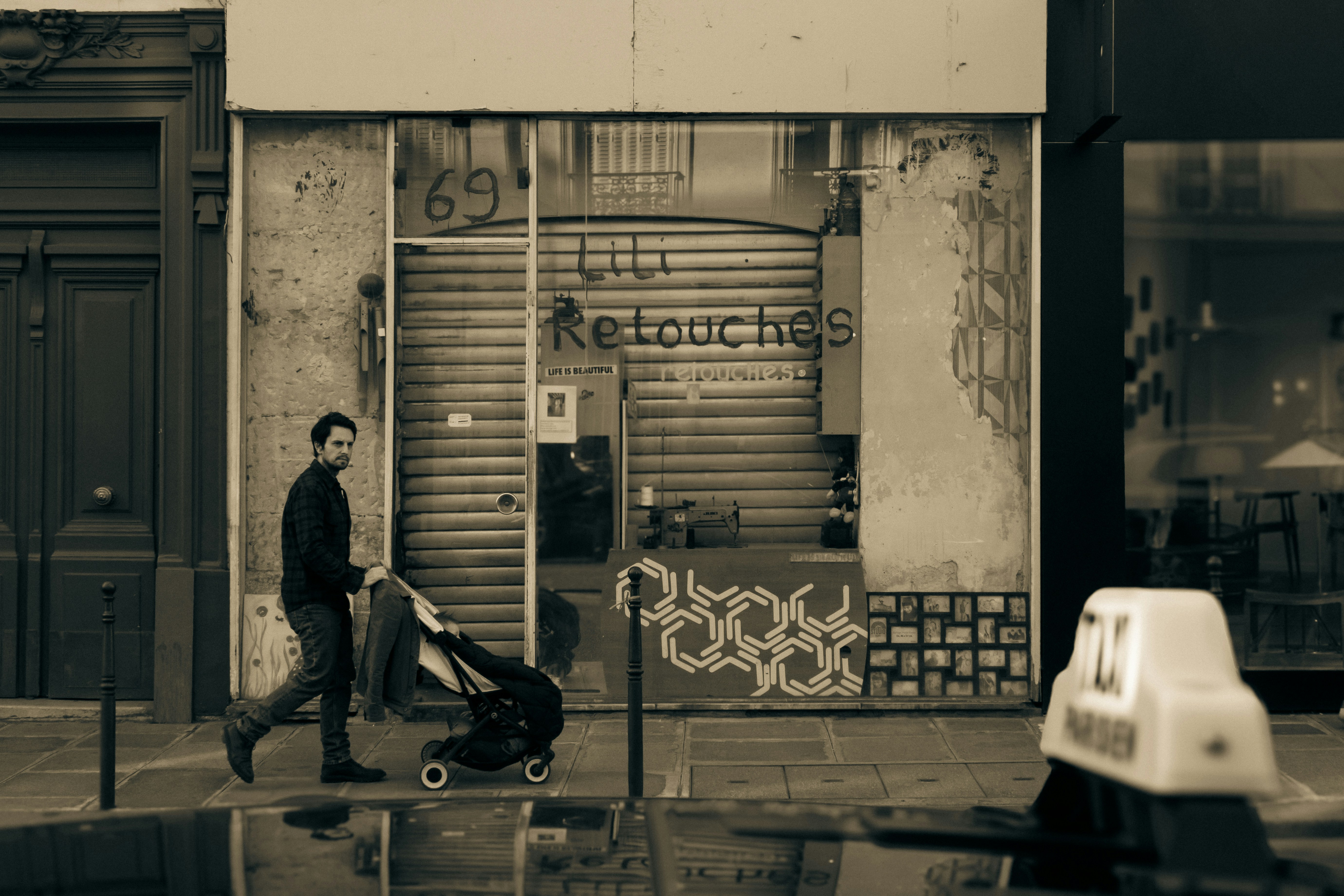Man pushing a stroller past a closed shop