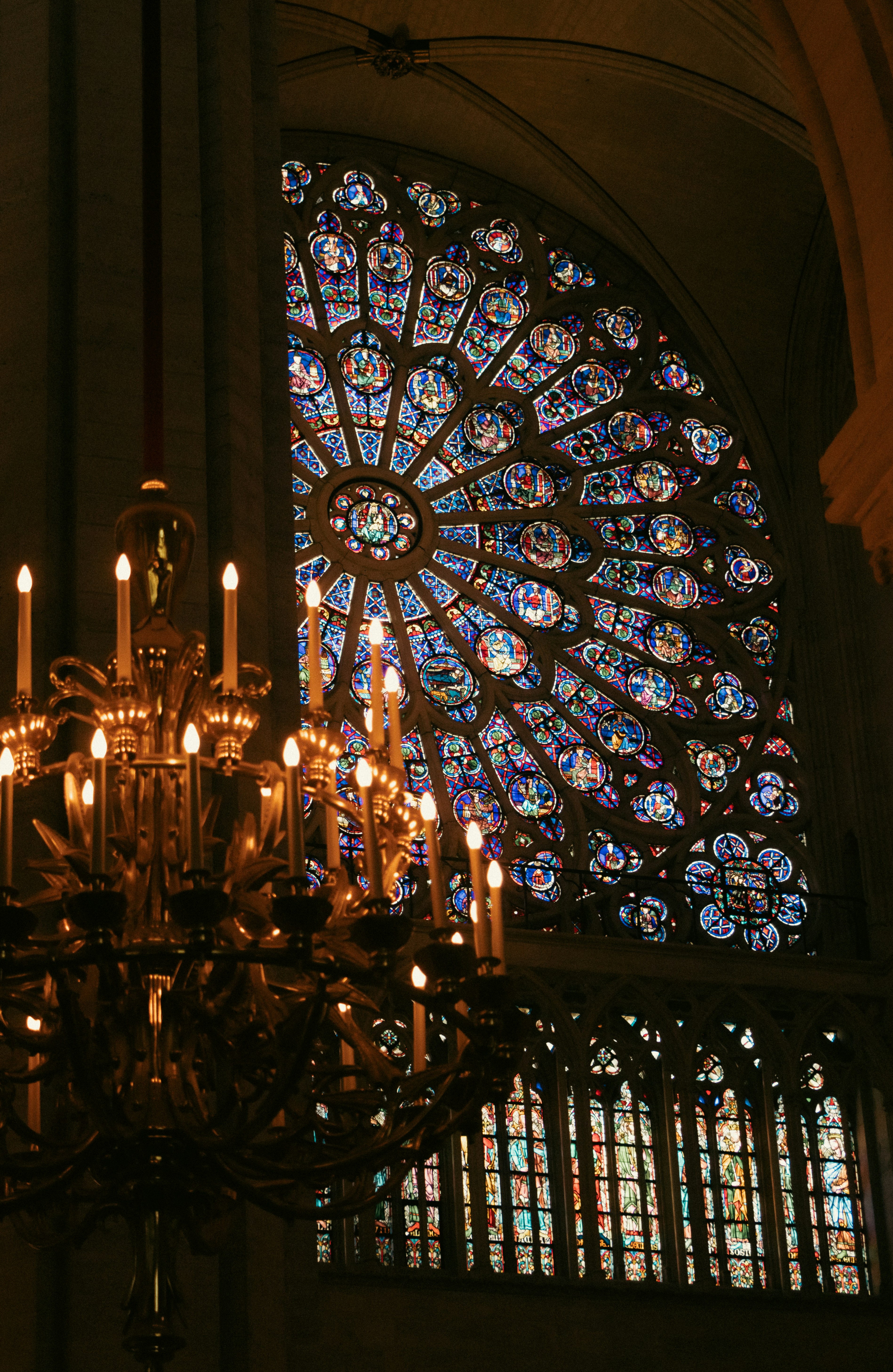 Ornate chandelier in front of a large stained glass window