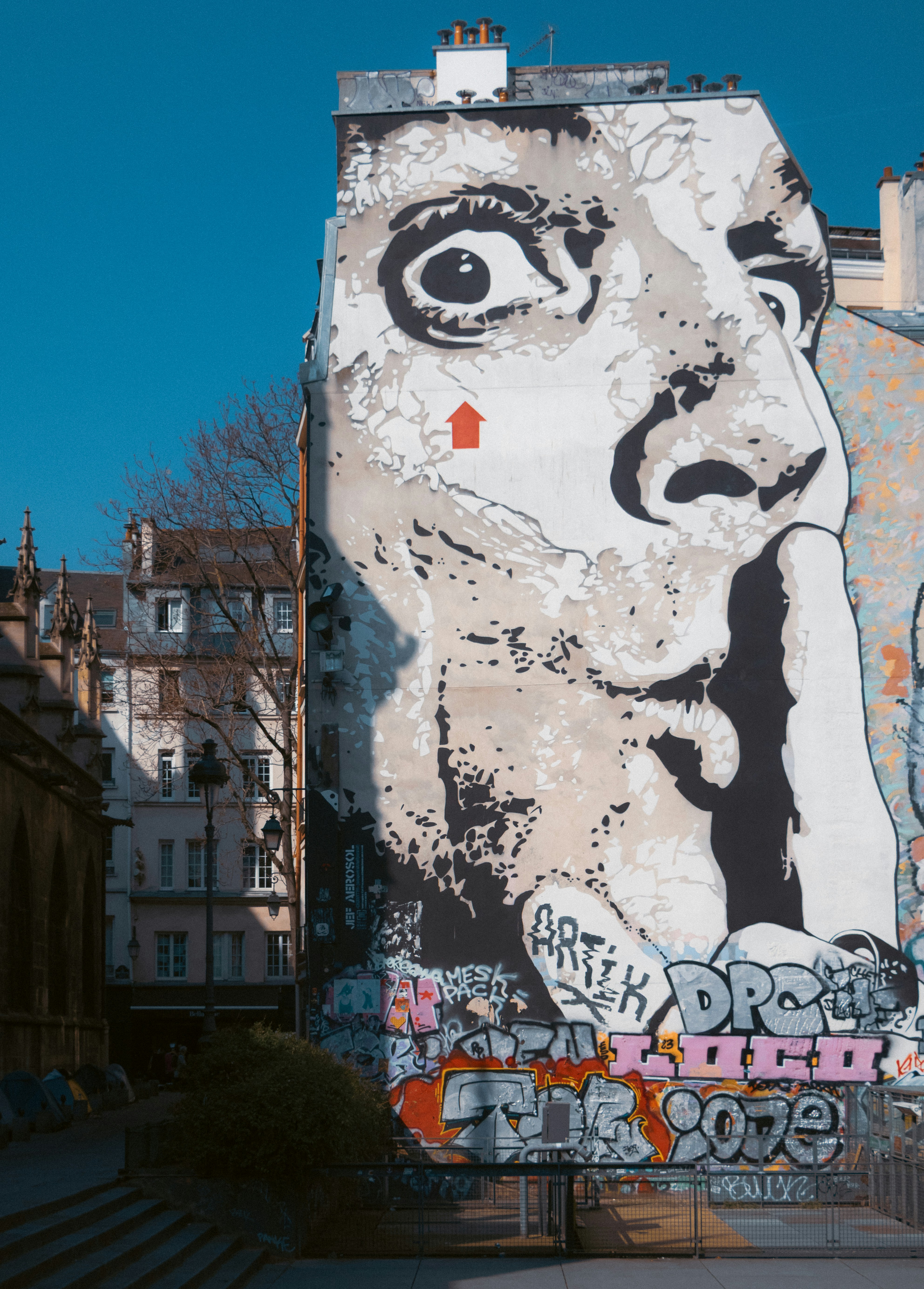Large mural of a face with finger to lips