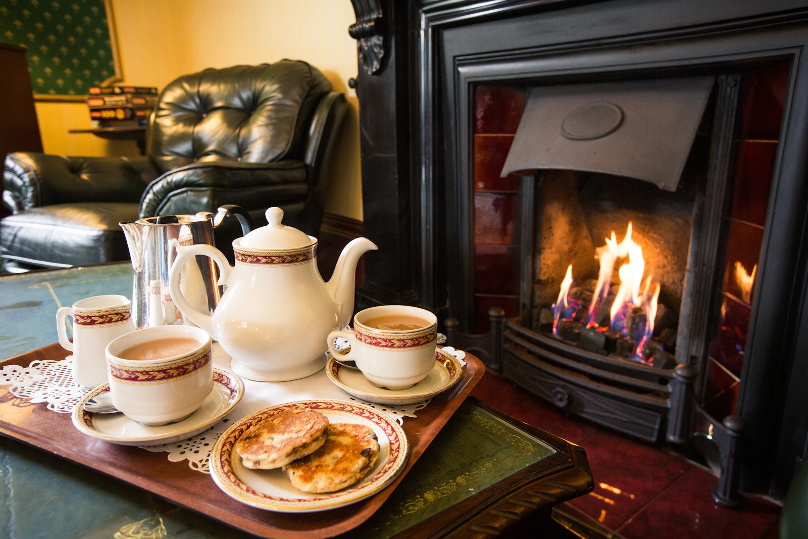 Tea for two on a tray beside a lit fireplace in a country-house sitting room