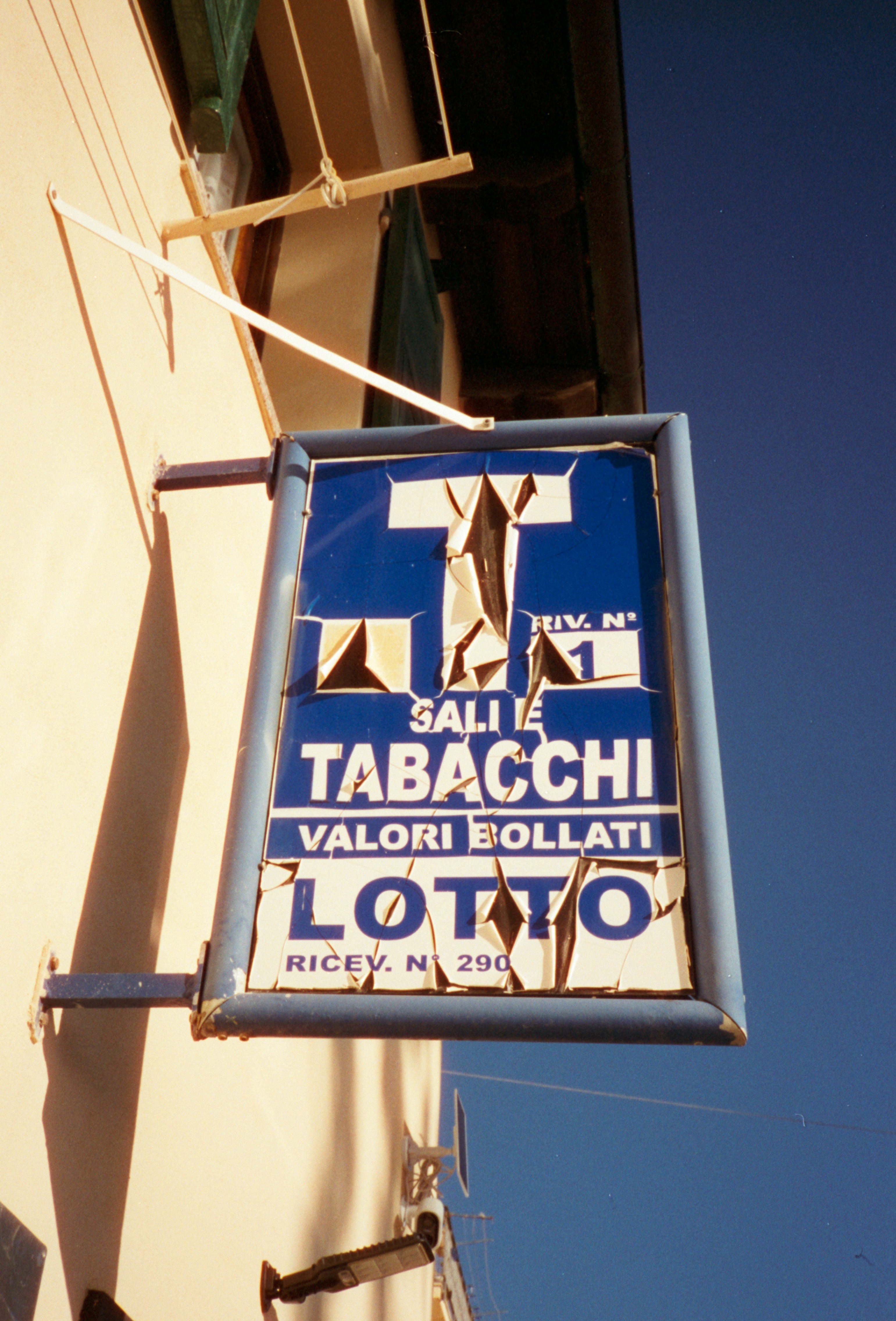 A weathered sign for tobacco, lotto, and stamps.
