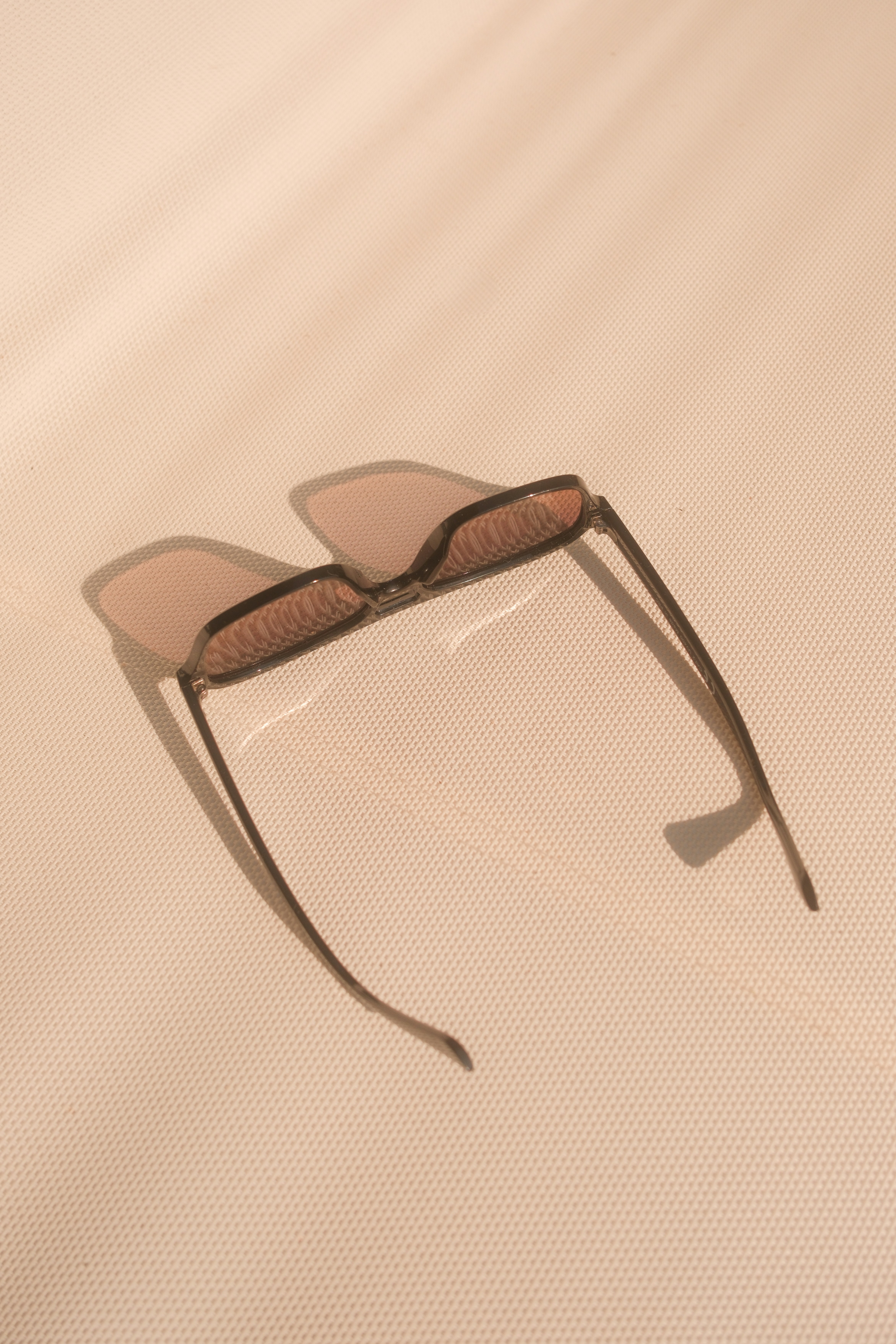 Stilvolle Sonnenbrille, die einen Schatten auf eine strukturierte Oberfläche werfen