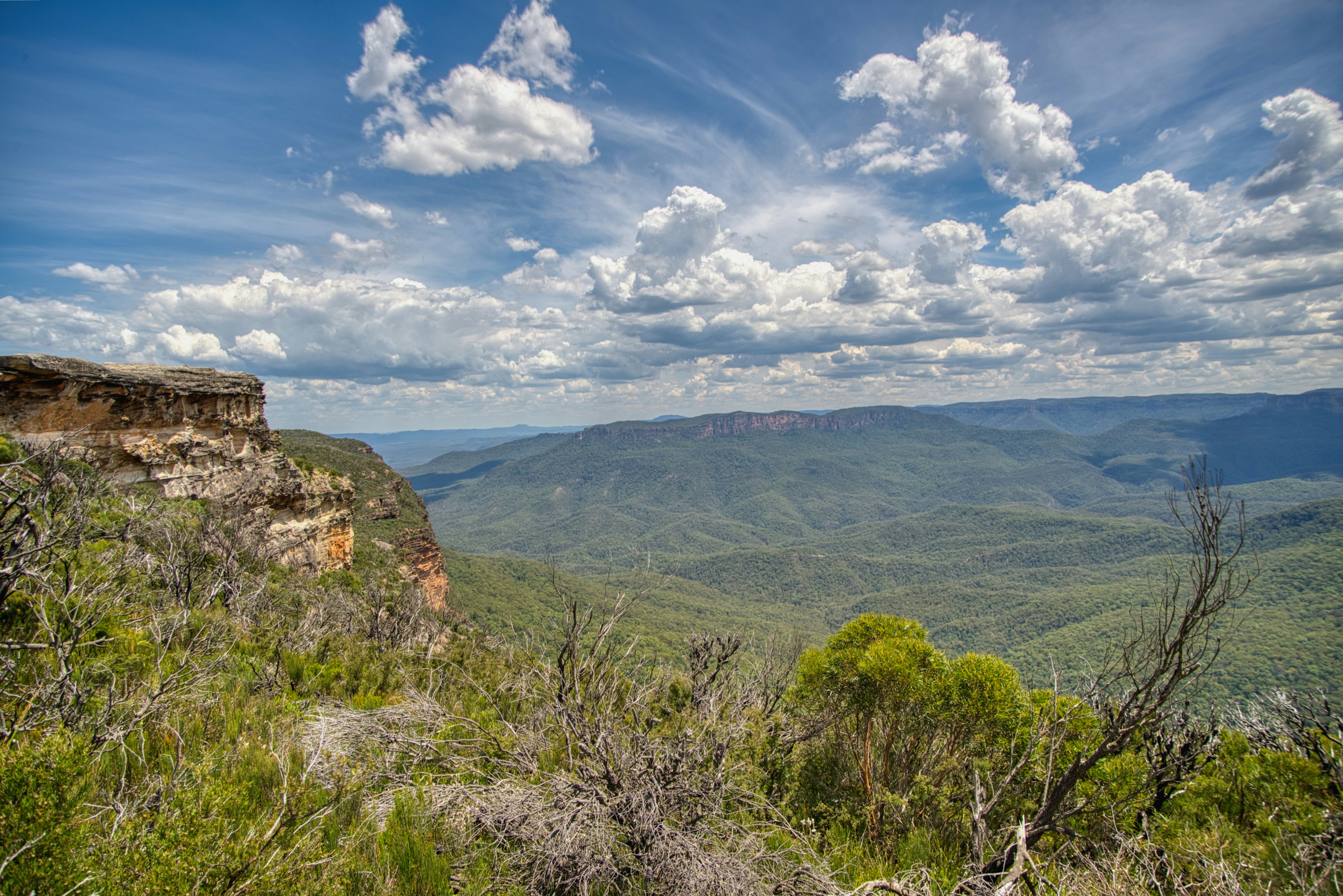 Vast green mountain landscape under a cloudy blue sky