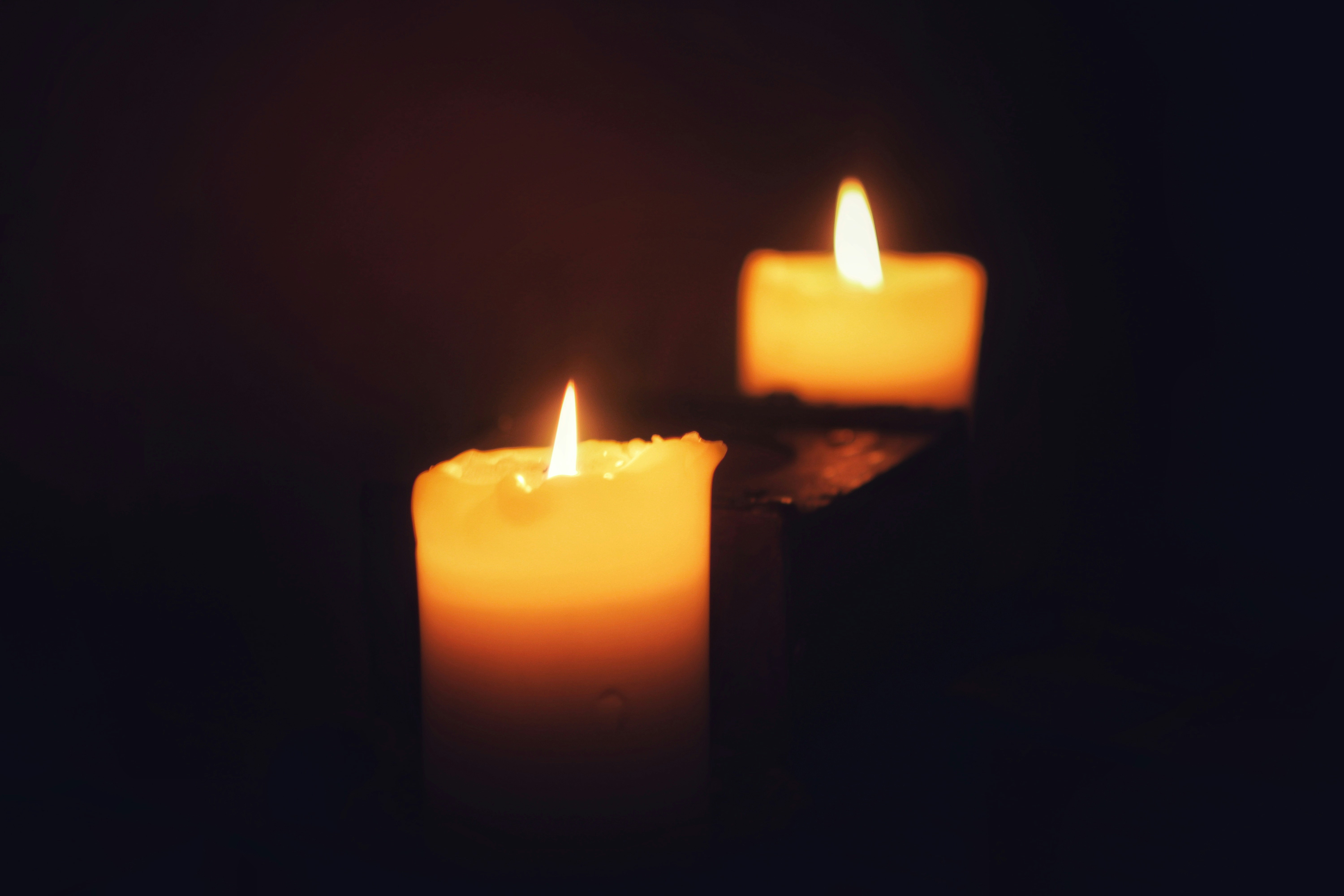 Two lit candles glowing in the dark