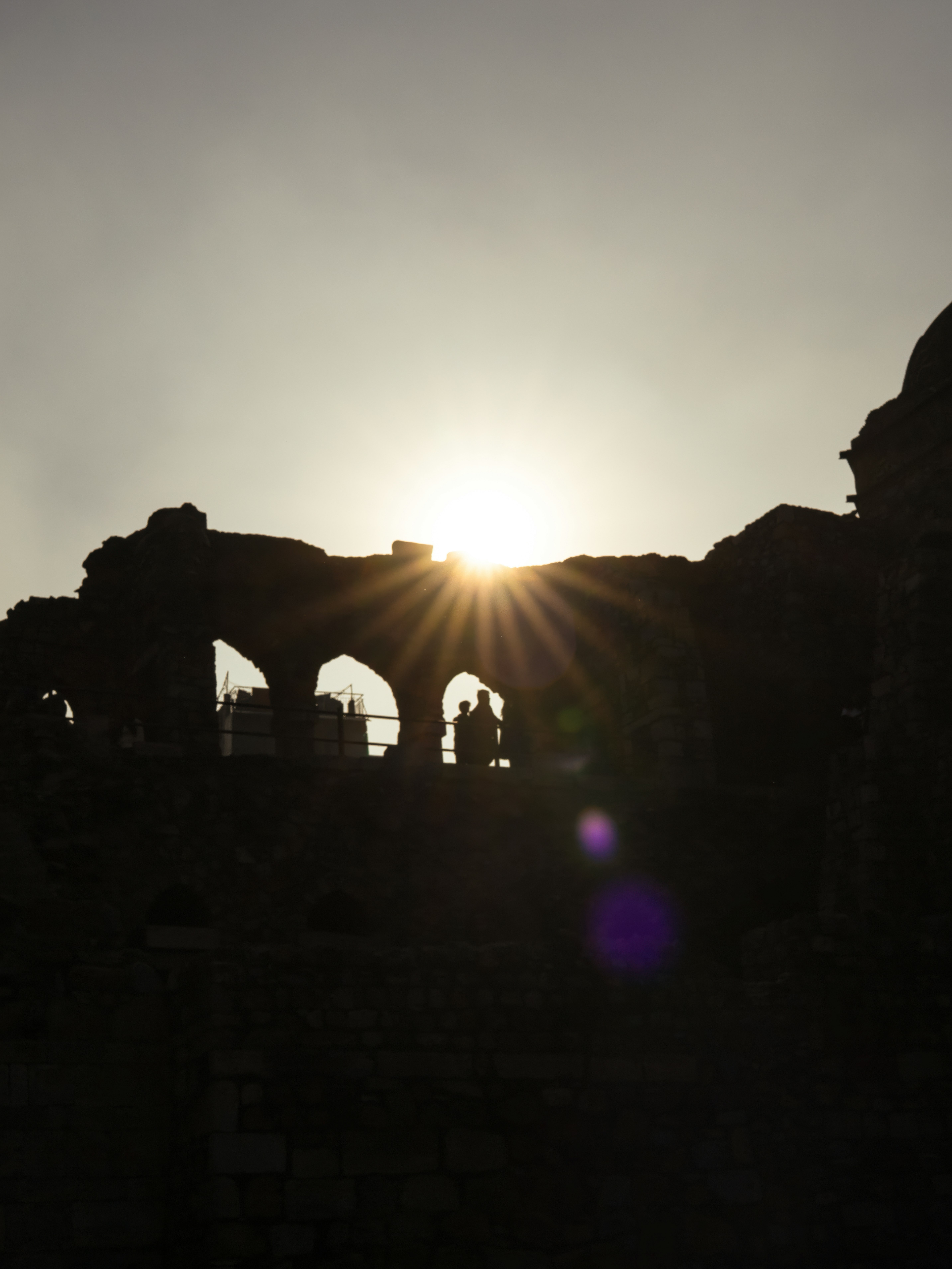 Silhouetted ruins with sunburst at sunset