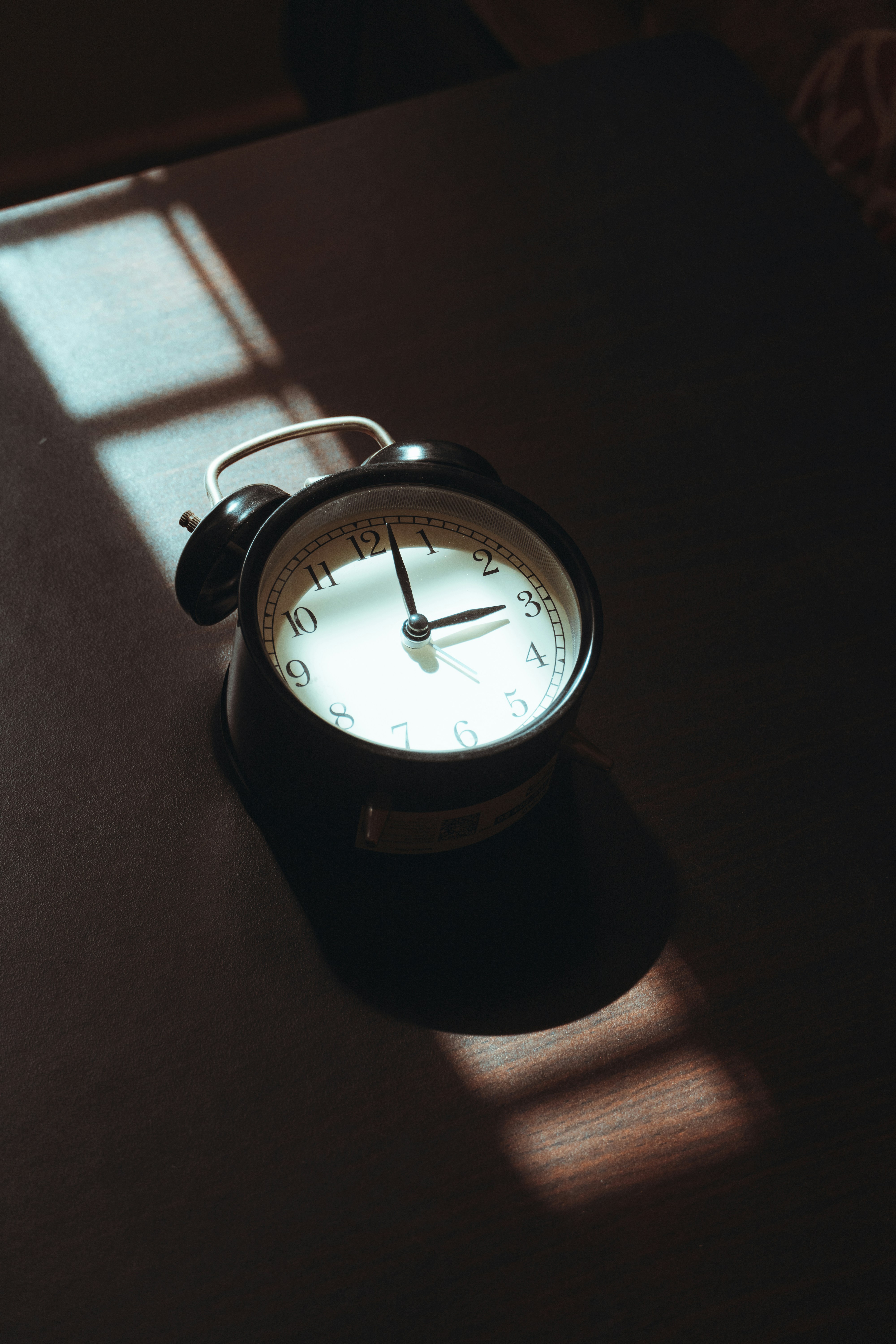 Alarm clock casting a shadow on a dark surface