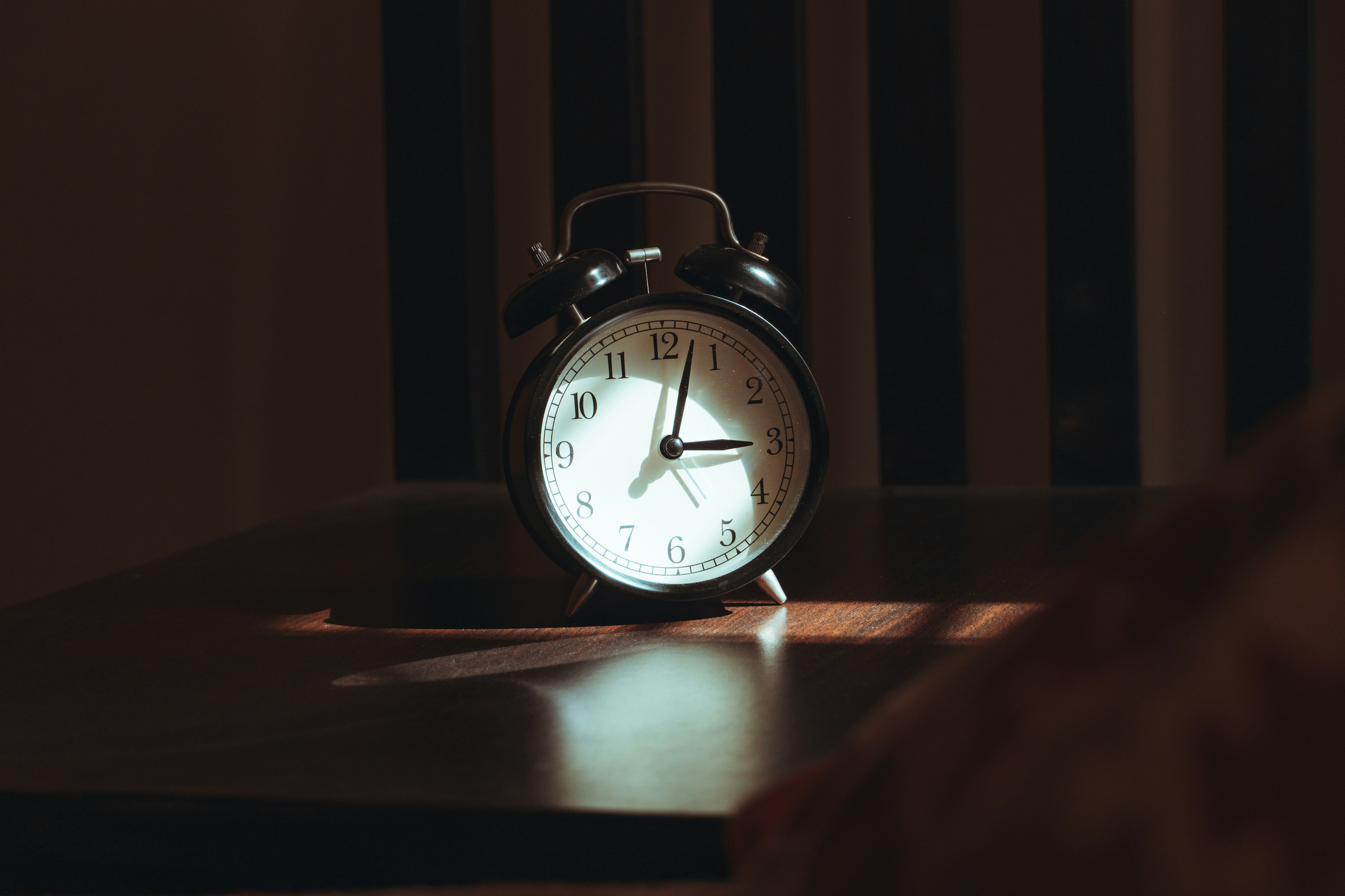 An alarm clock on a wooden table at night