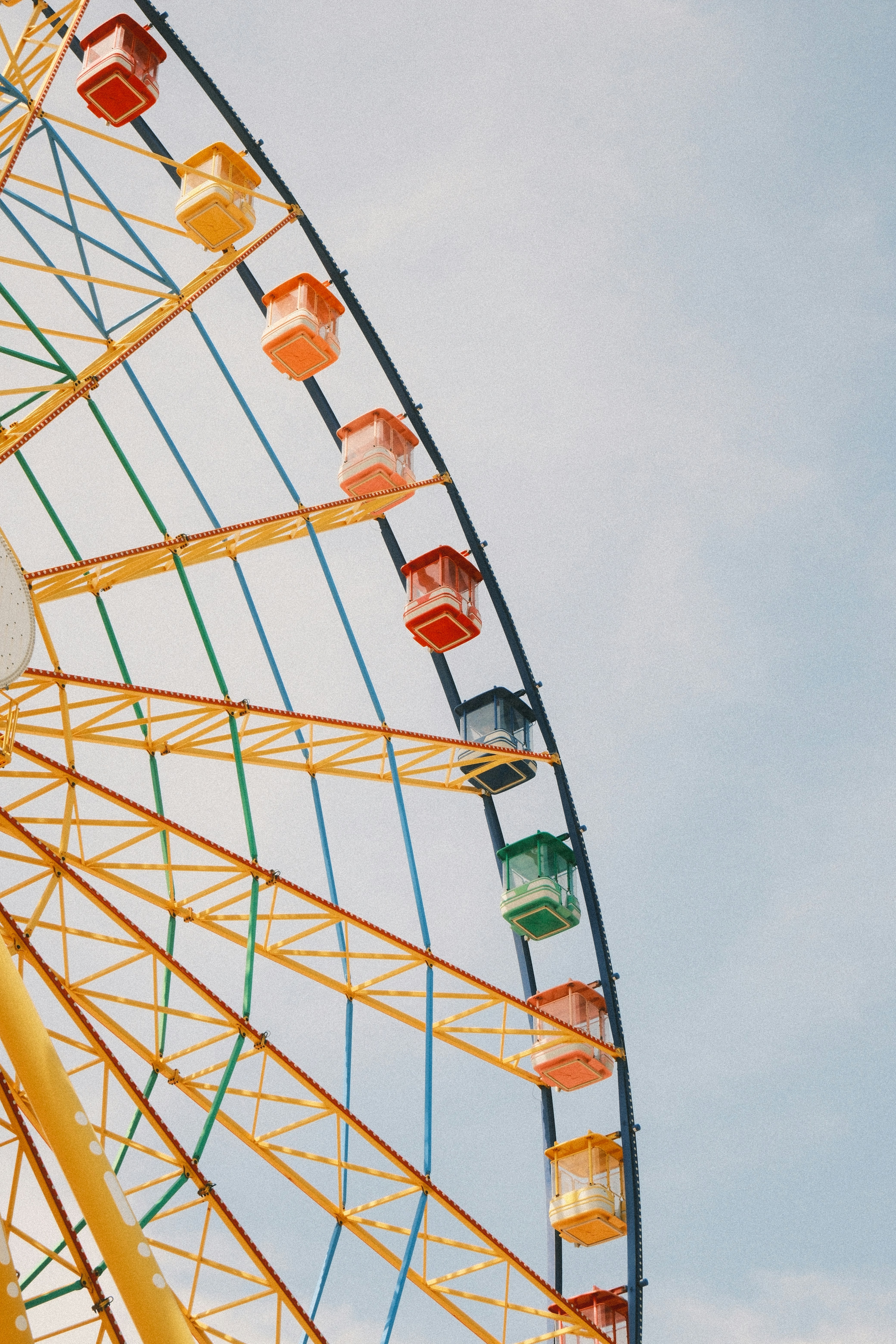 Colorful gondolas on a yellow ferris wheel against sky