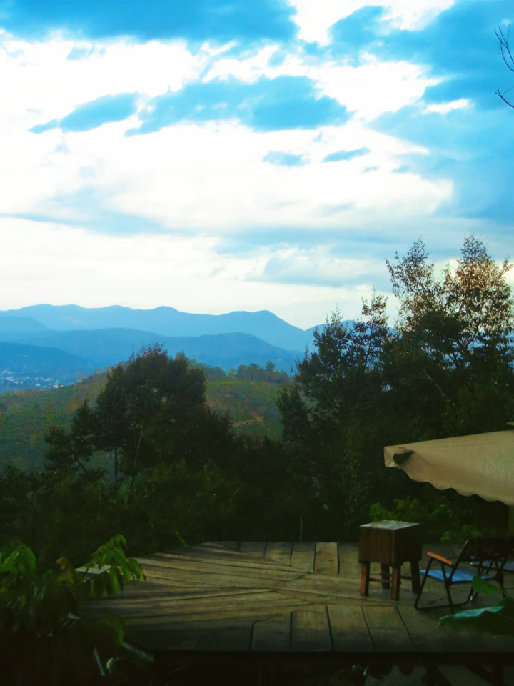 A wooden deck opening onto hills and open sky.