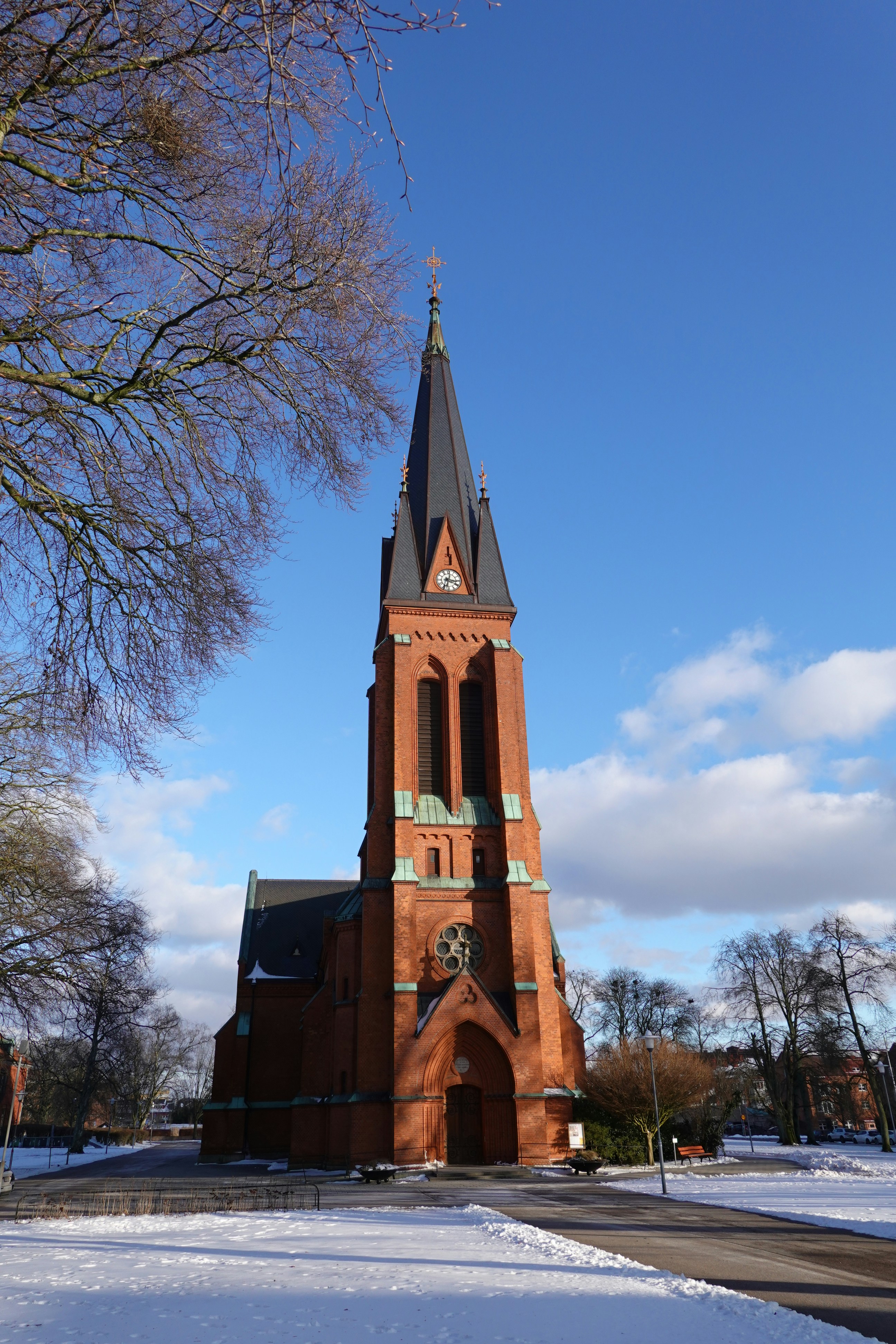 A tall brick church with a steeple under blue sky.