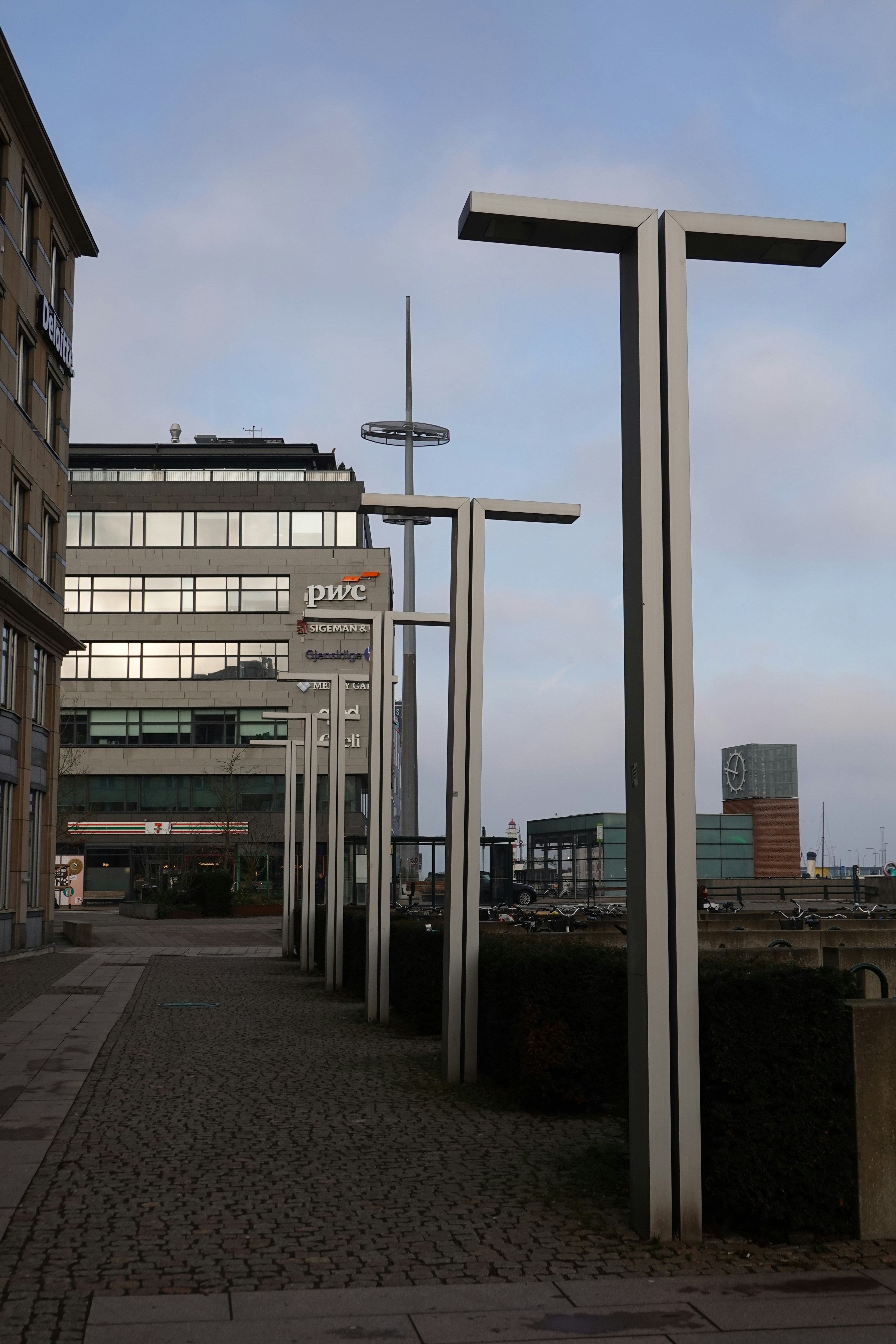 Modern streetlights line a walkway with buildings behind.
