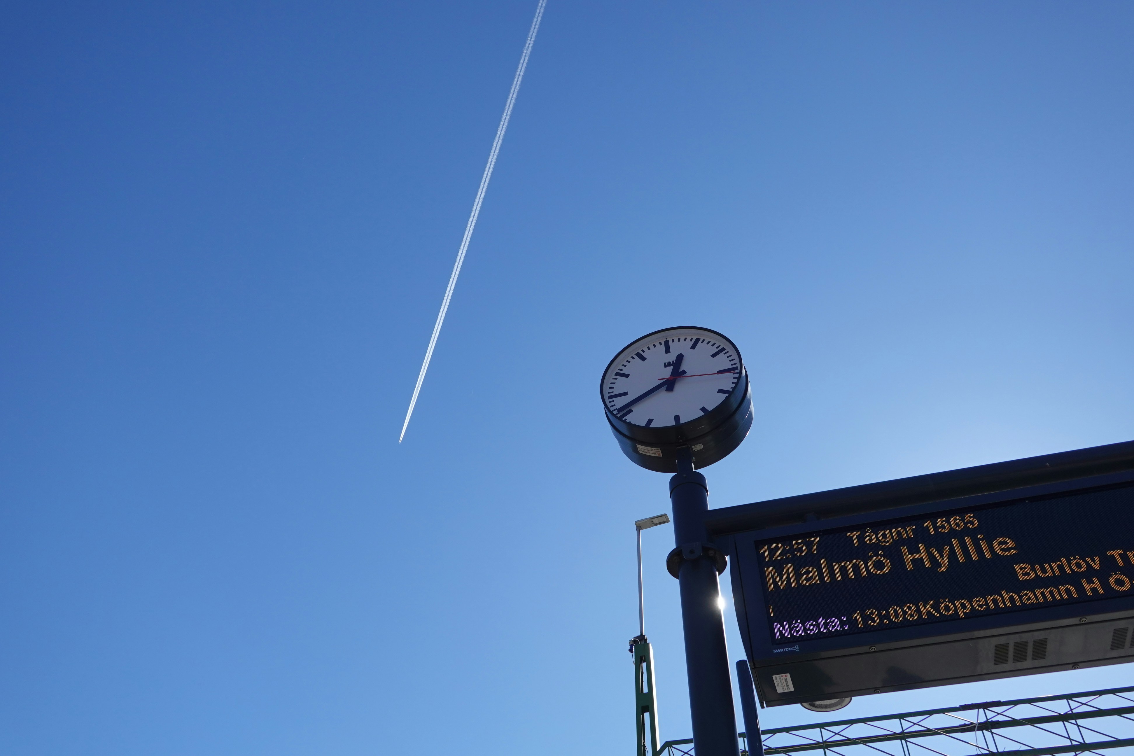 Un orologio e un orario di treni sotto un cielo azzurro limpido