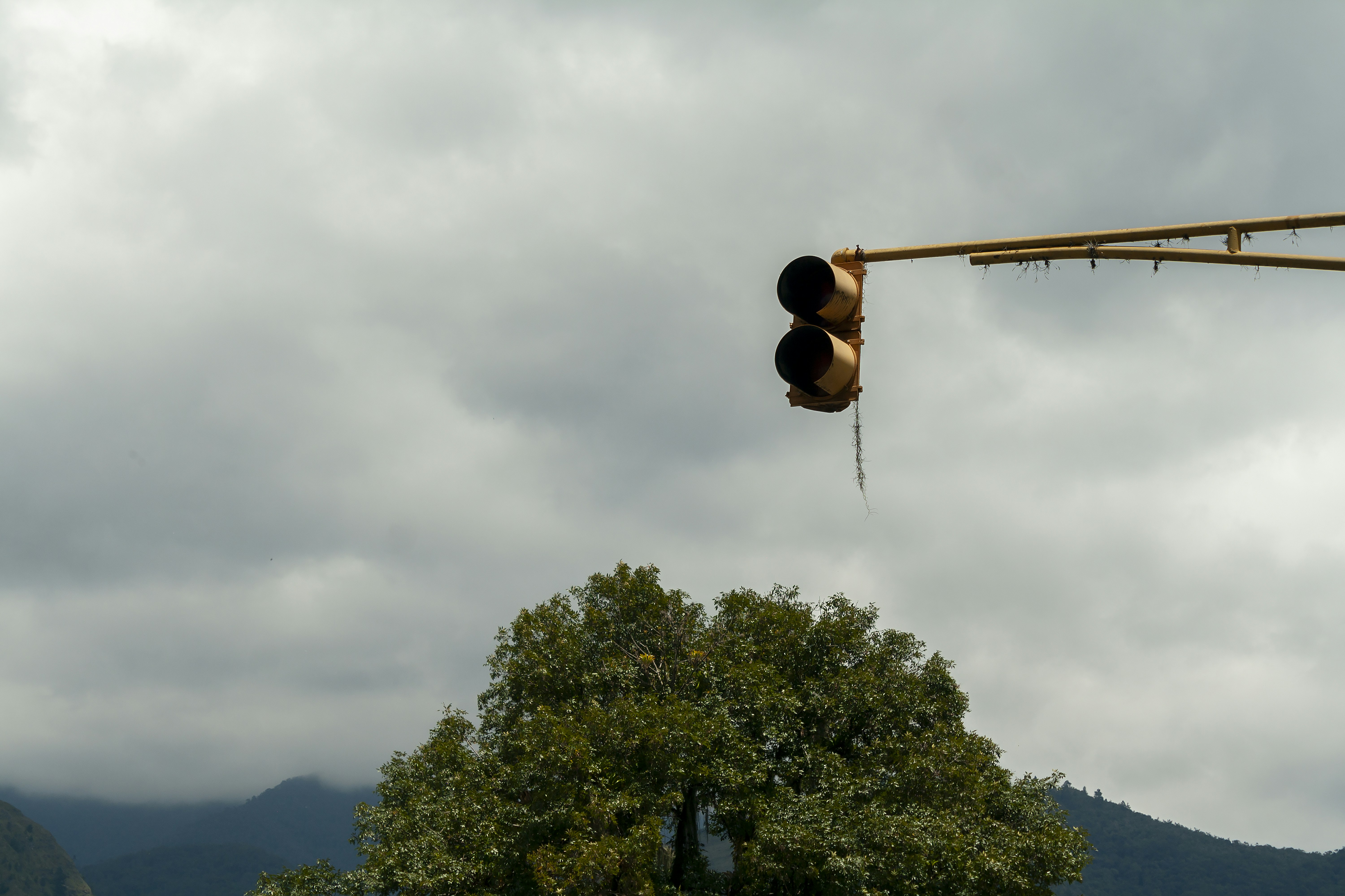Traffic light hangs against cloudy sky