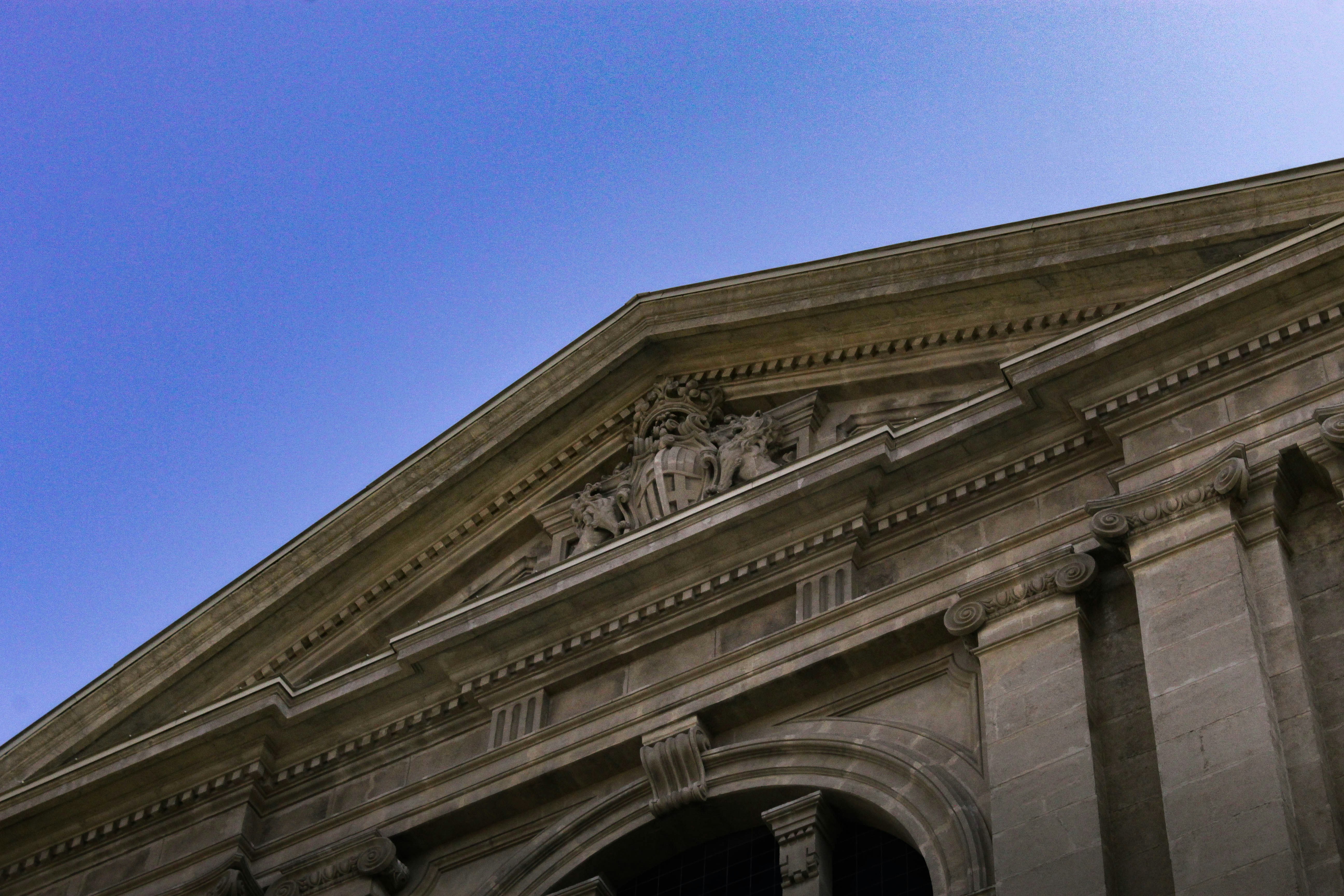Facciata classica dell'edificio con frontone dettagliato sotto il cielo azzurro