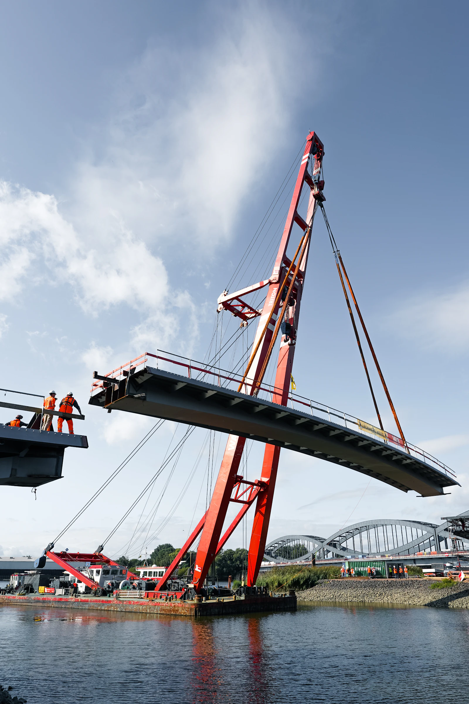 A crane lifting a section of a bridge into place over water