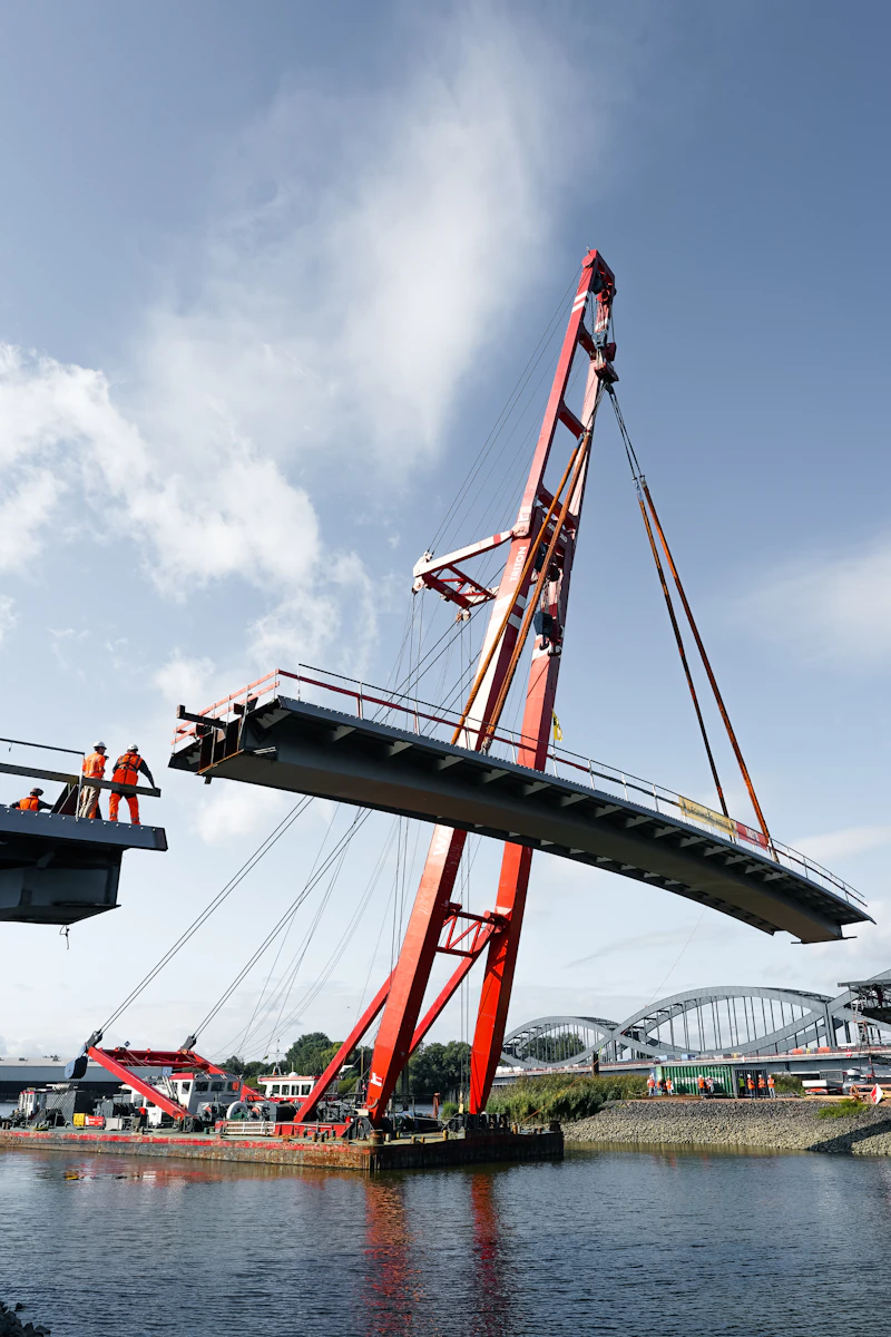 A crane lifting a section of a bridge into place over water