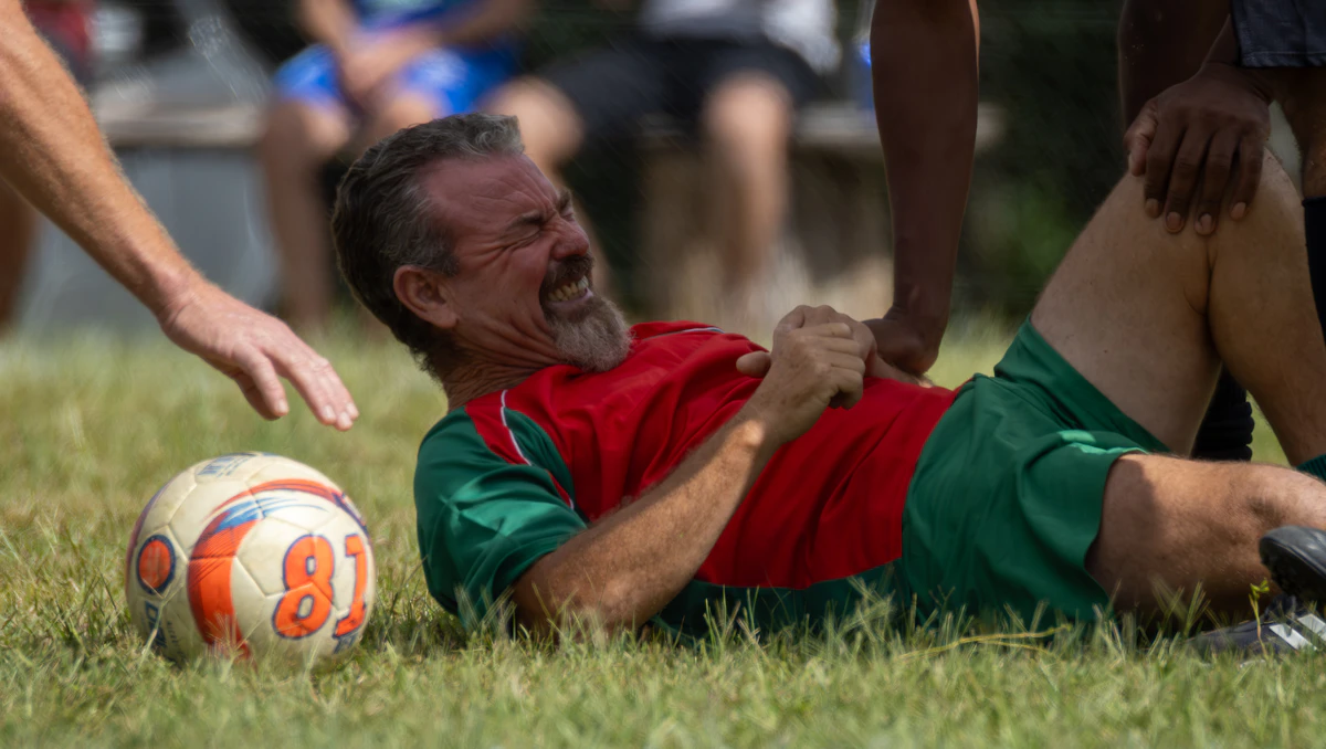 Man in a soccer uniform down on the grass after a leg injury, illustrating the soft-tissue damage Thymosin Beta-4 and TB-500 aim to help repair.