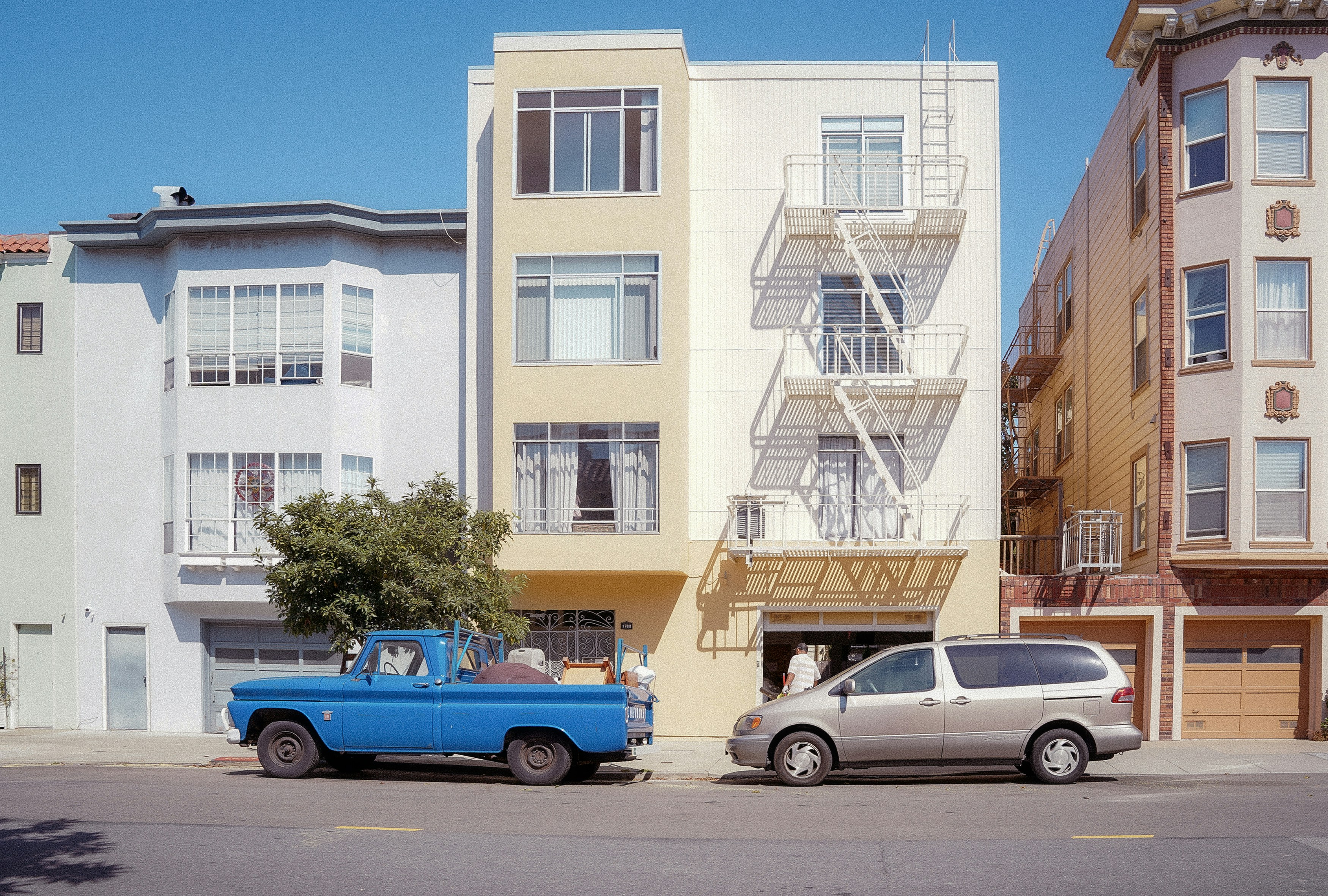 A blue truck and silver van parked outside buildings