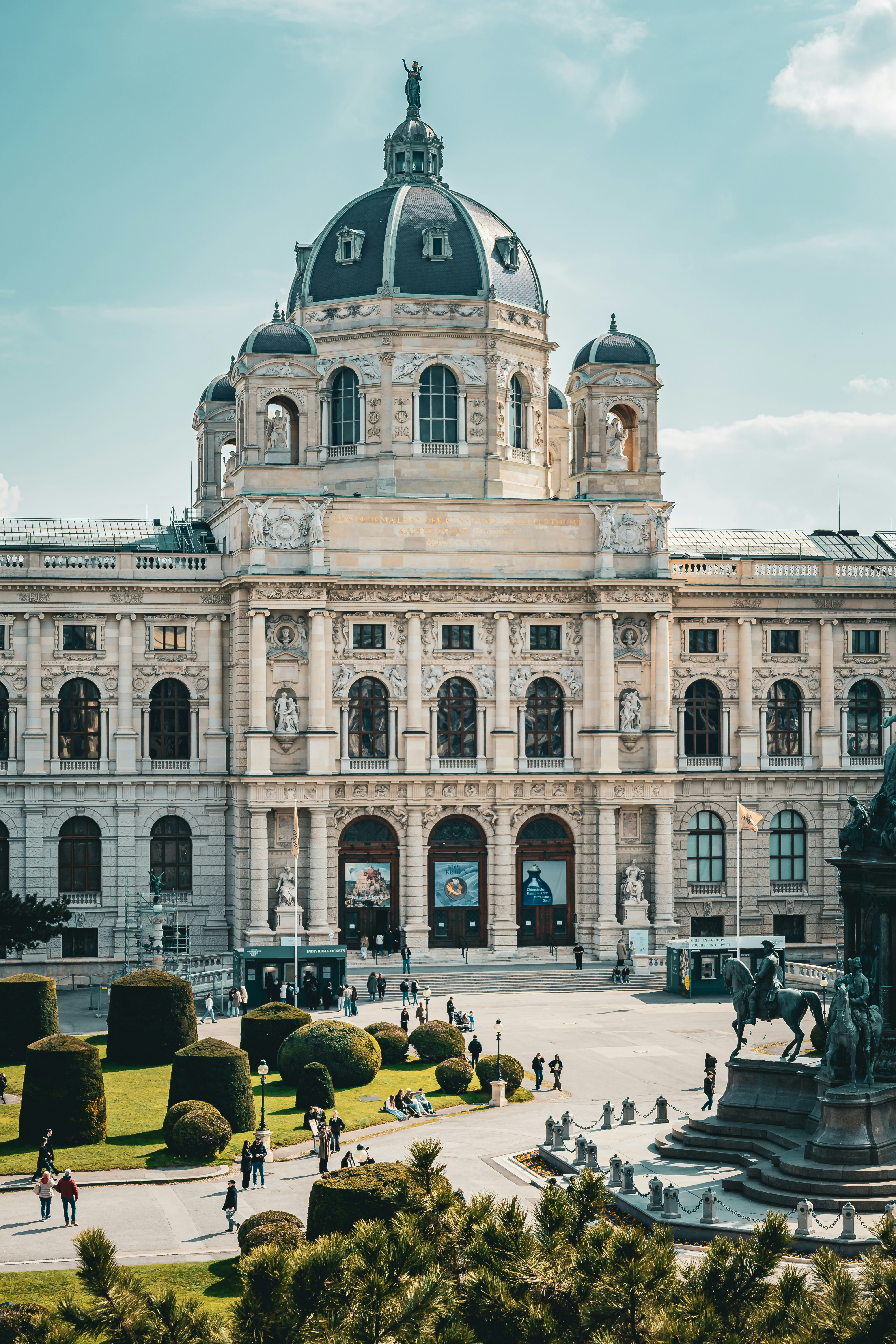 Grand historic building with manicured gardens and people