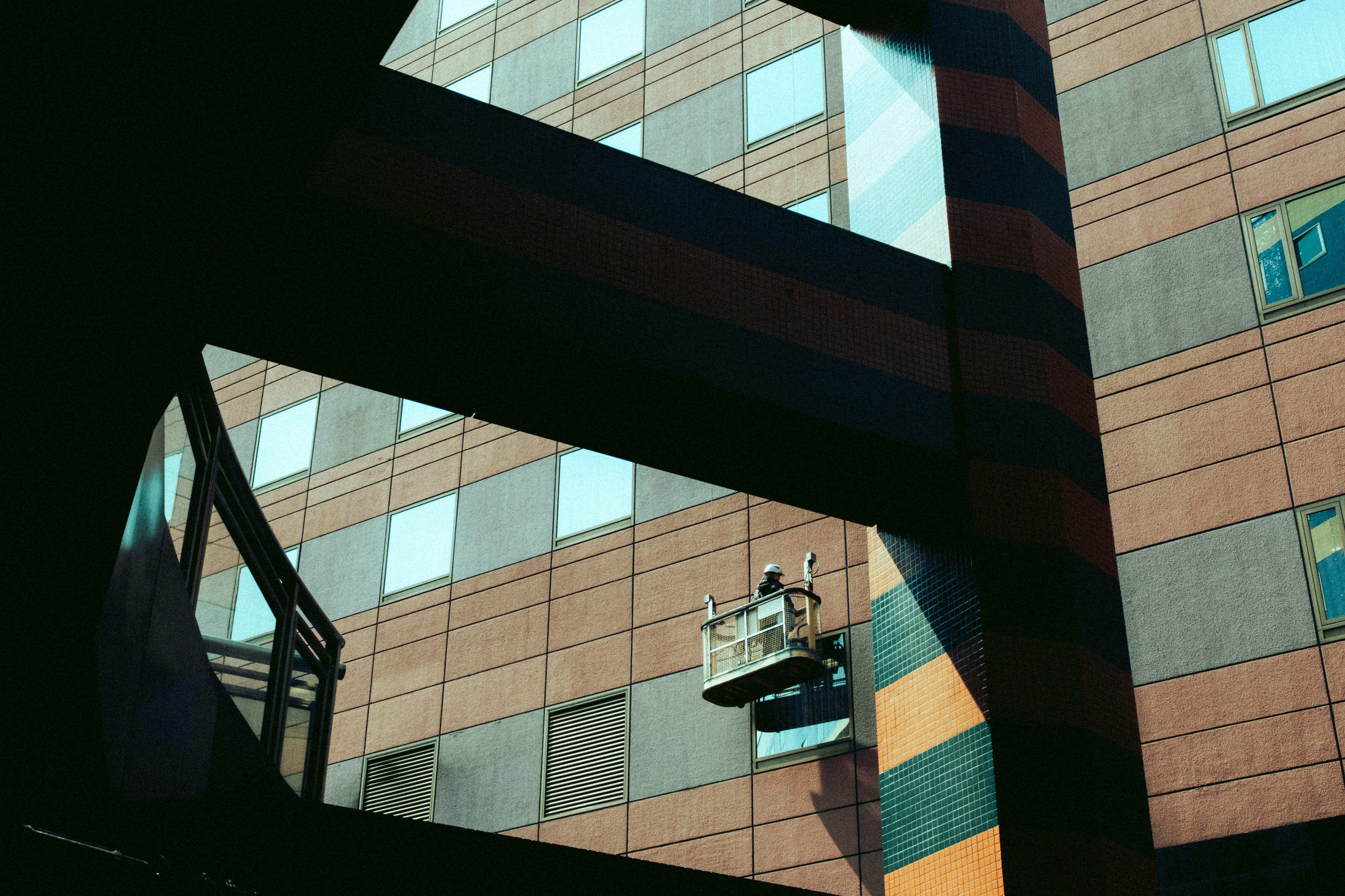 Worker cleaning windows on a modern building exterior.