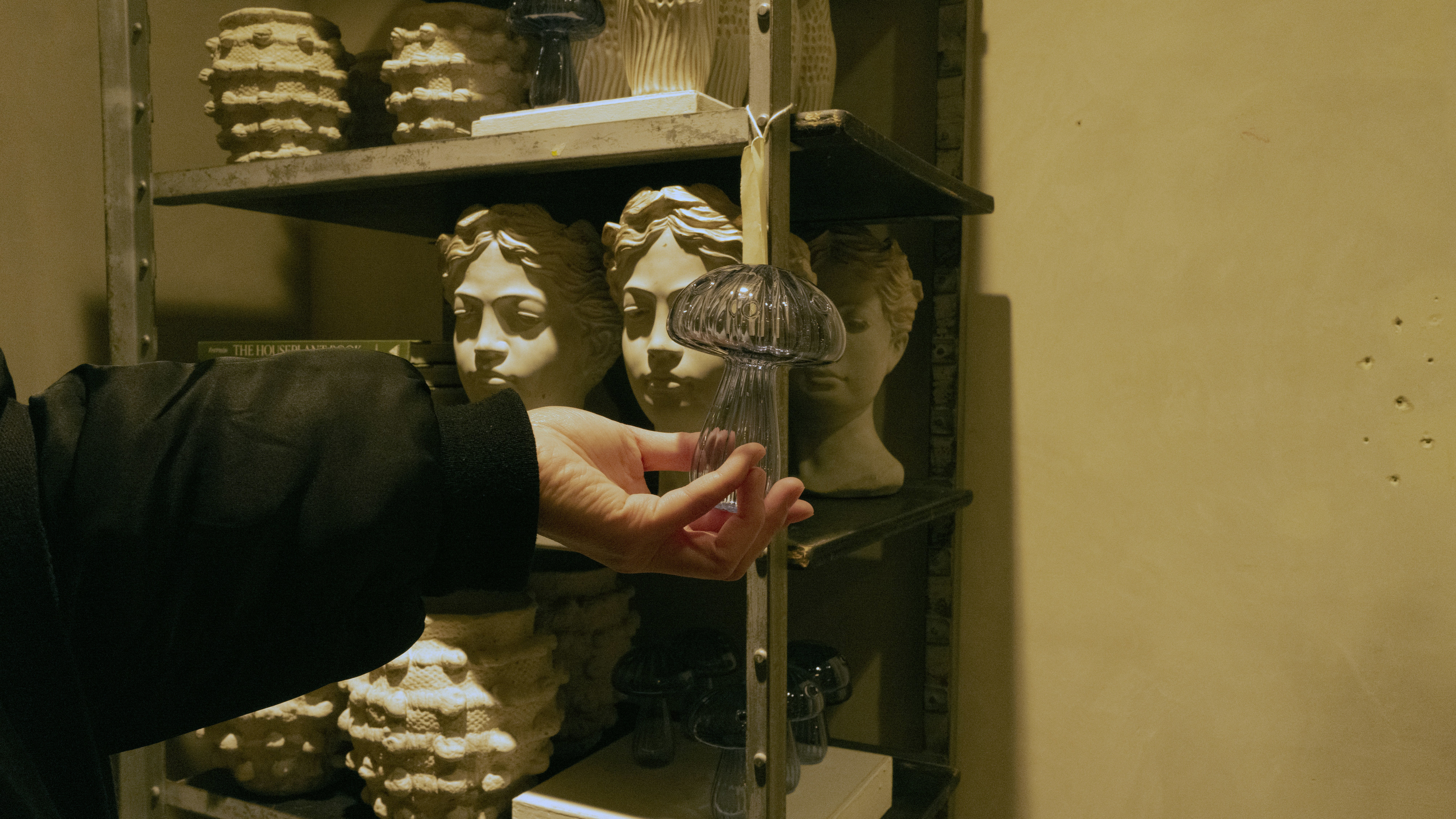Main tendue vers des bustes antiques sur une étagère
