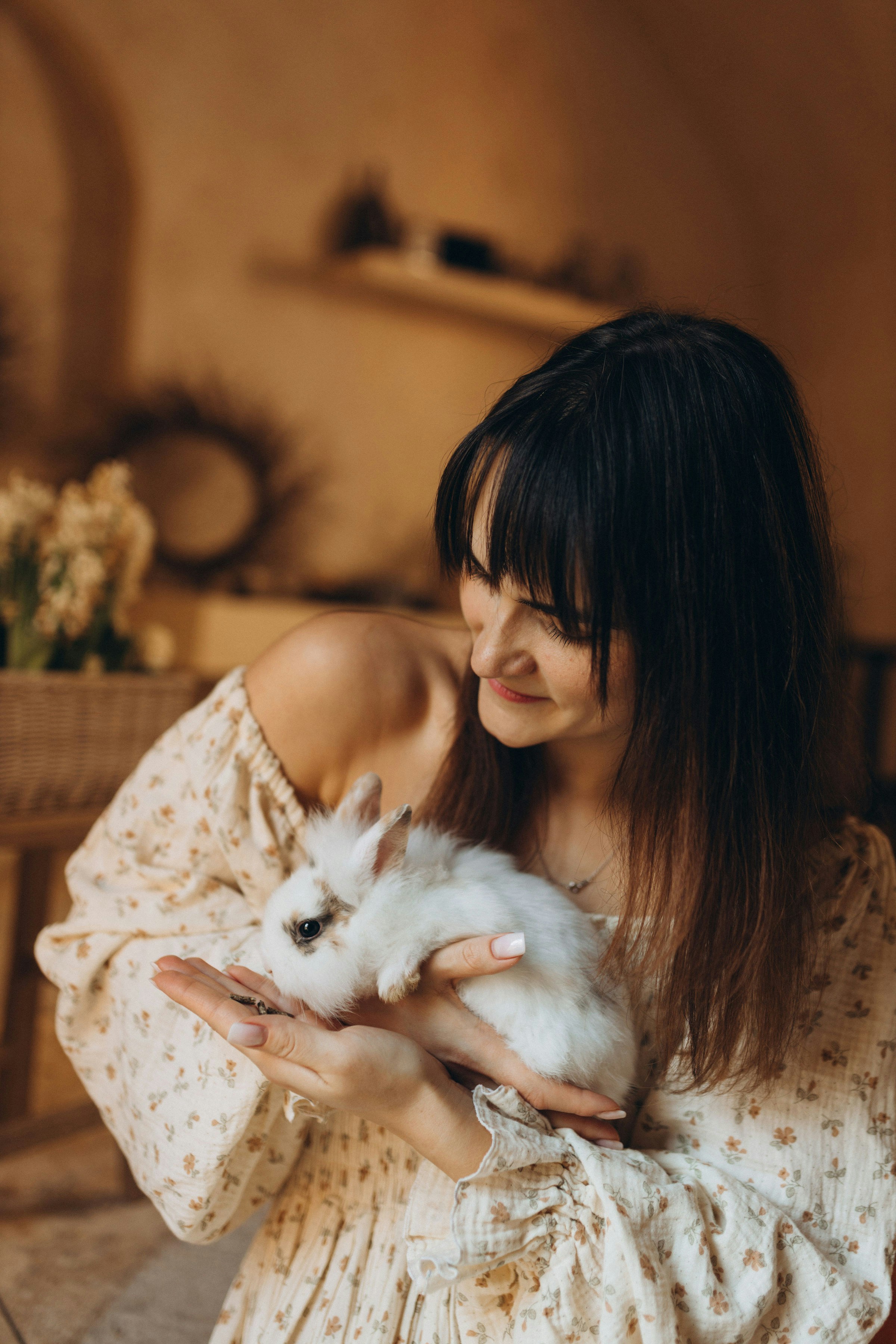 Eine Frau, die ein kleines, flauschiges weißes Kaninchen hält.
