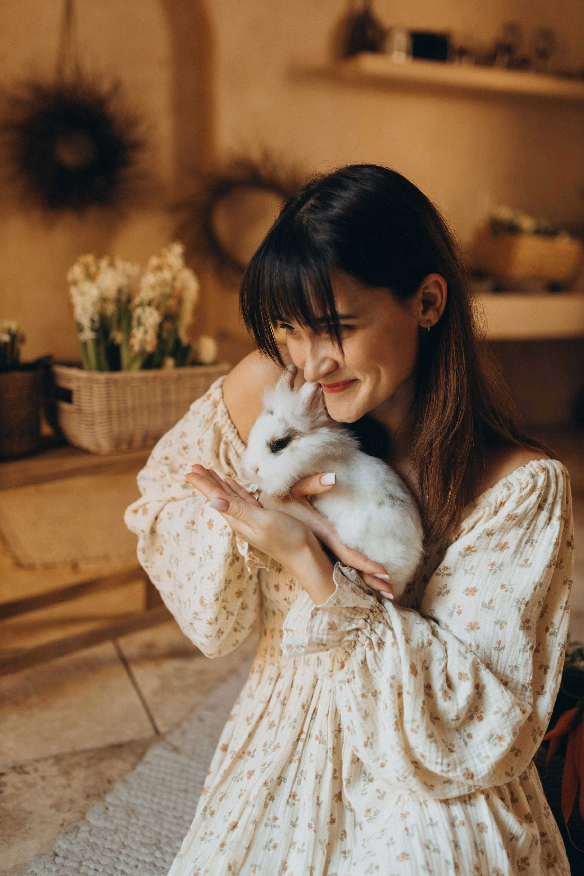 Eine junge Frau hält sanft ein kleines weißes Kaninchen in der Hand.