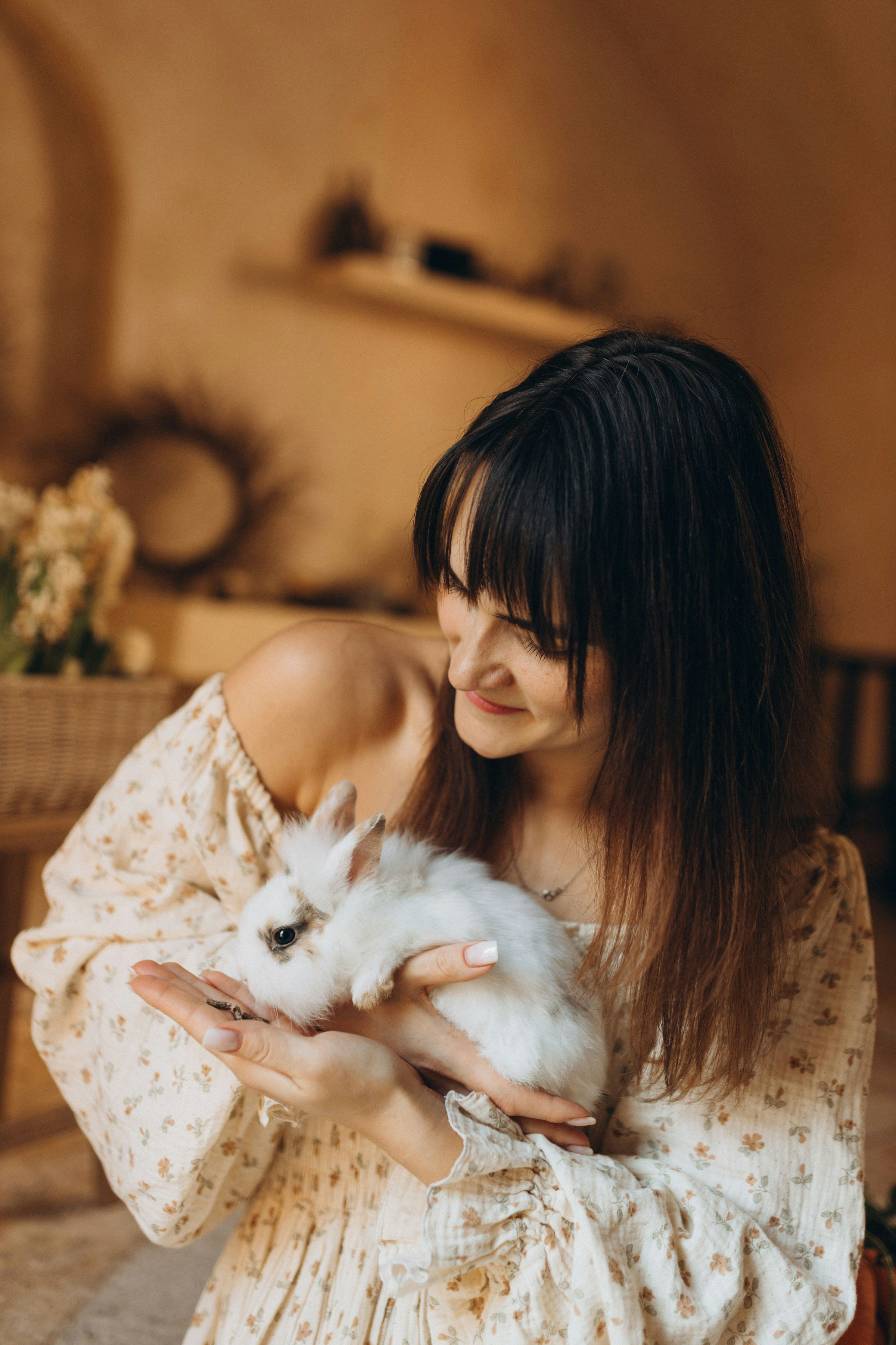 Eine Frau, die sanft zwei kleine weiße Kaninchen hält.