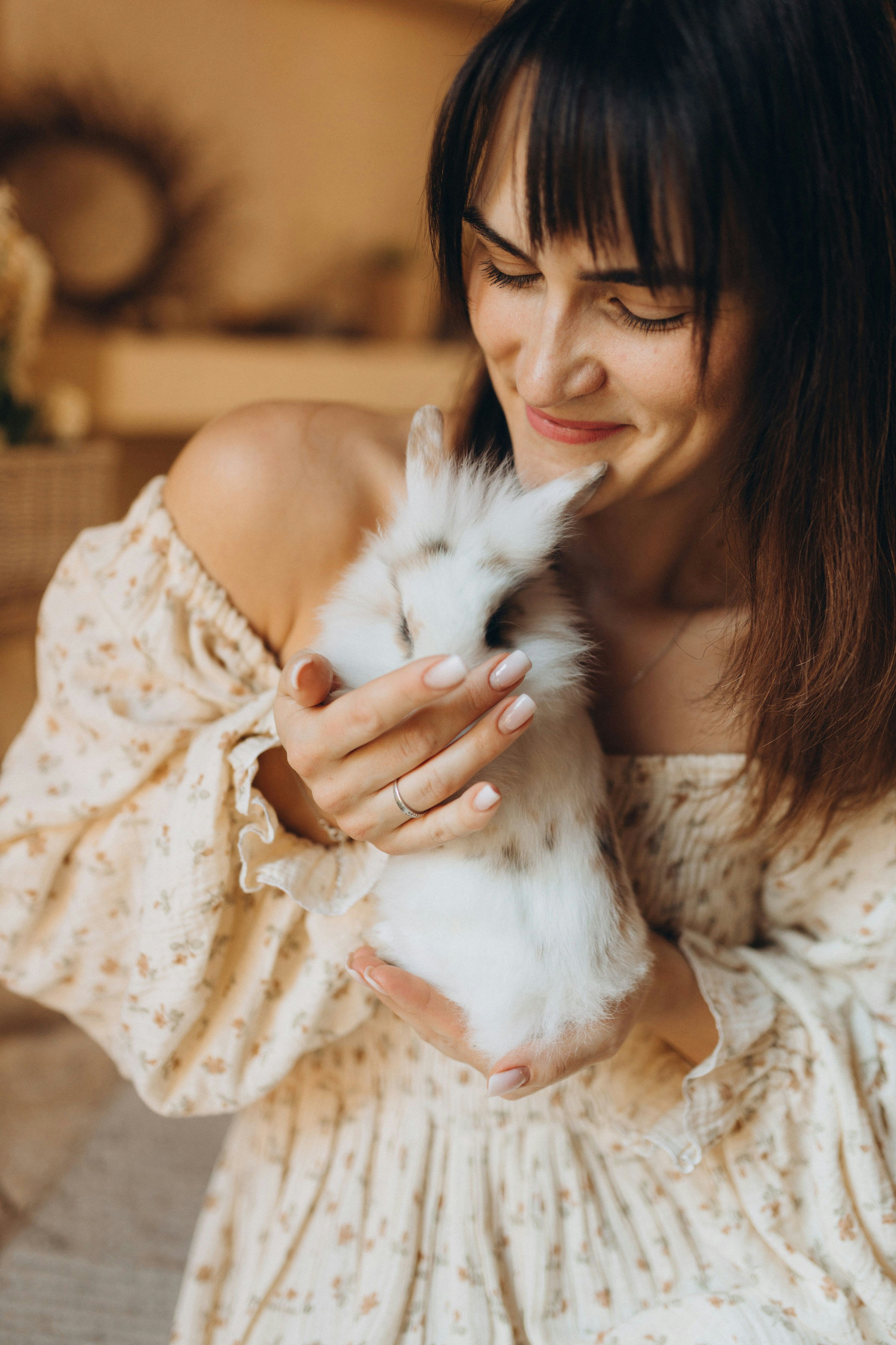 Eine Frau hält sanft ein kleines weißes Kaninchen.