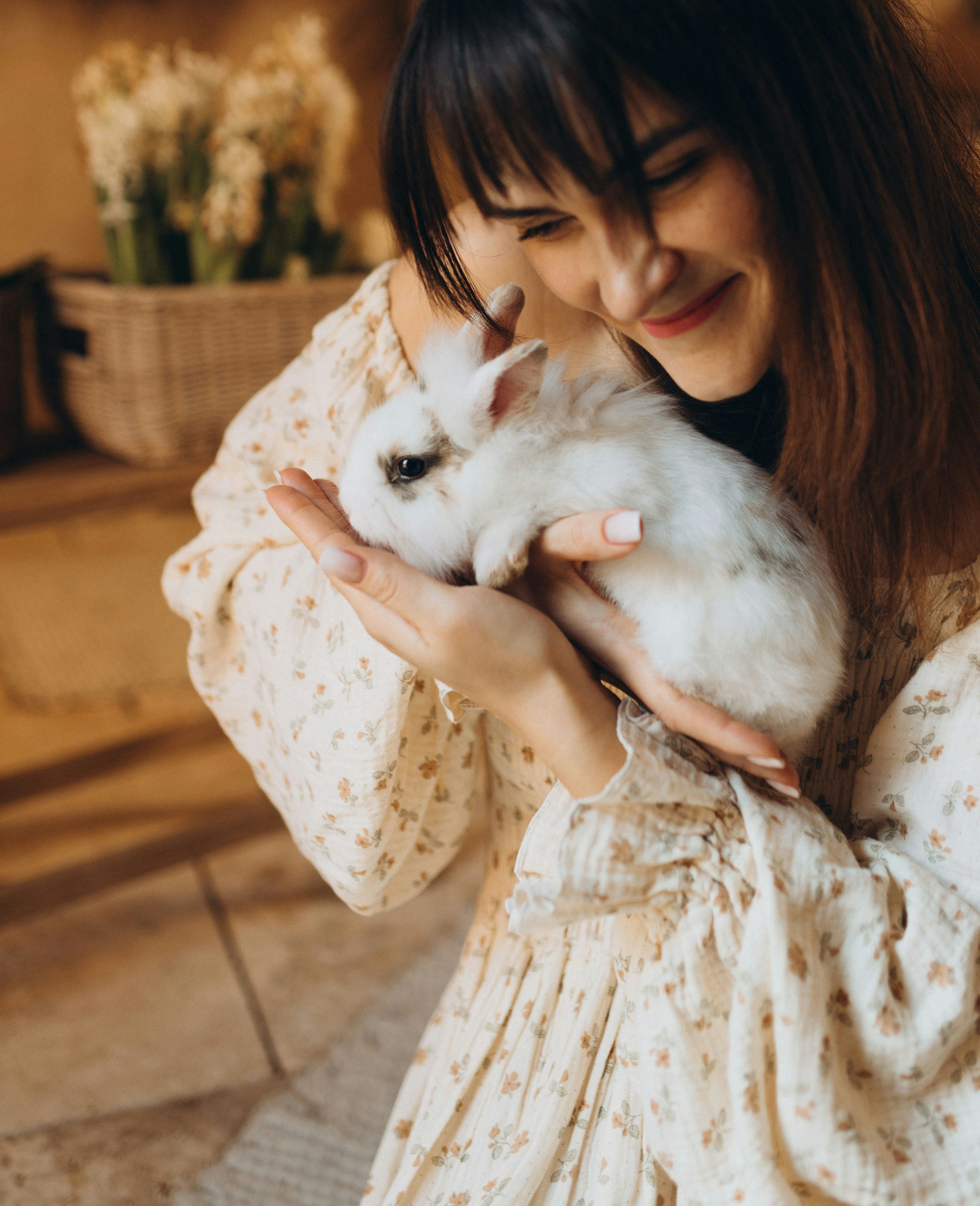 Eine Frau hält sanft ein kleines weißes Kaninchen.