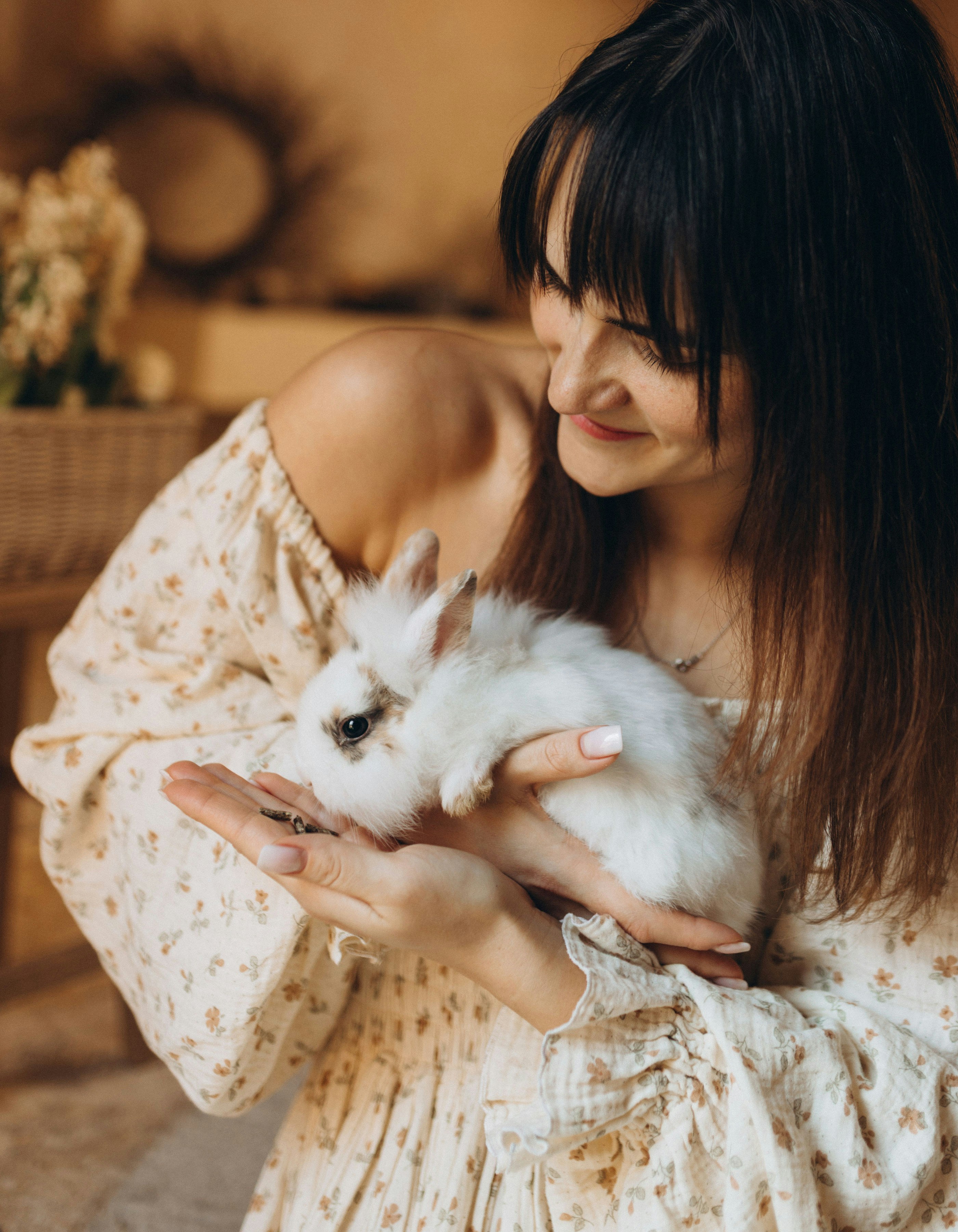 Eine Frau hält sanft ein kleines weißes Kaninchen.