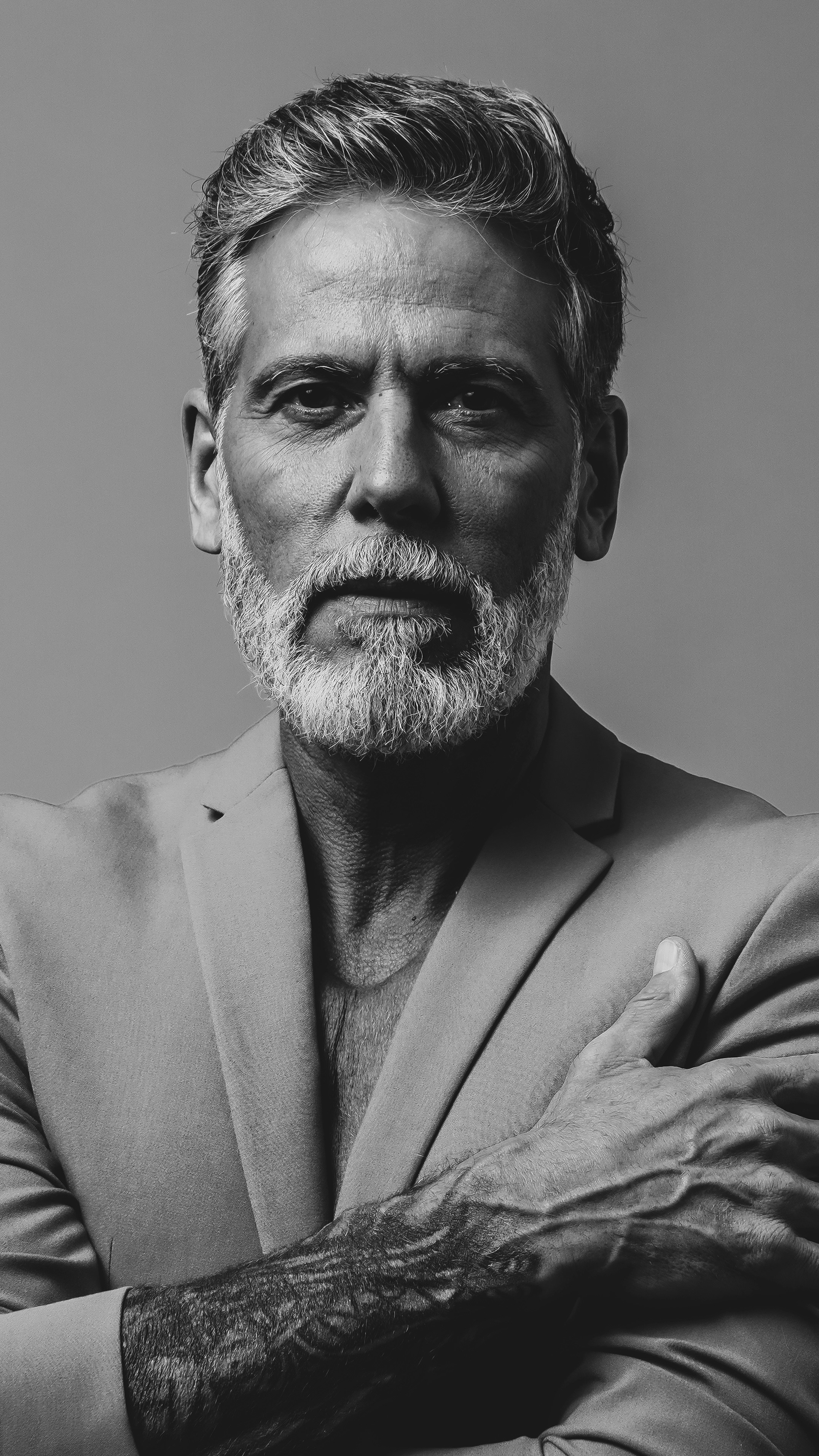Mature man with beard wearing a suit with arms crossed