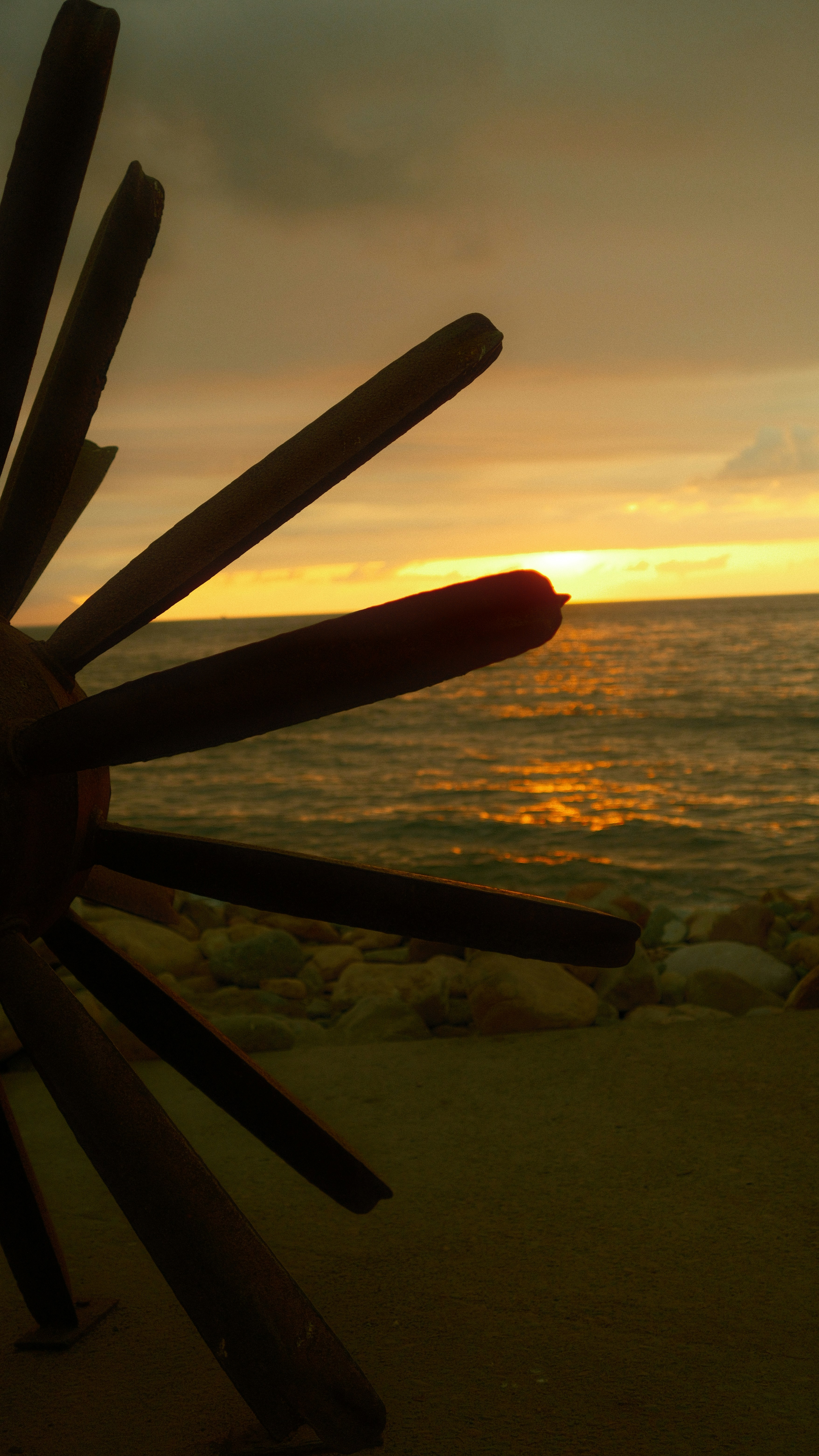 Sunset over the ocean with a decorative wooden wheel
